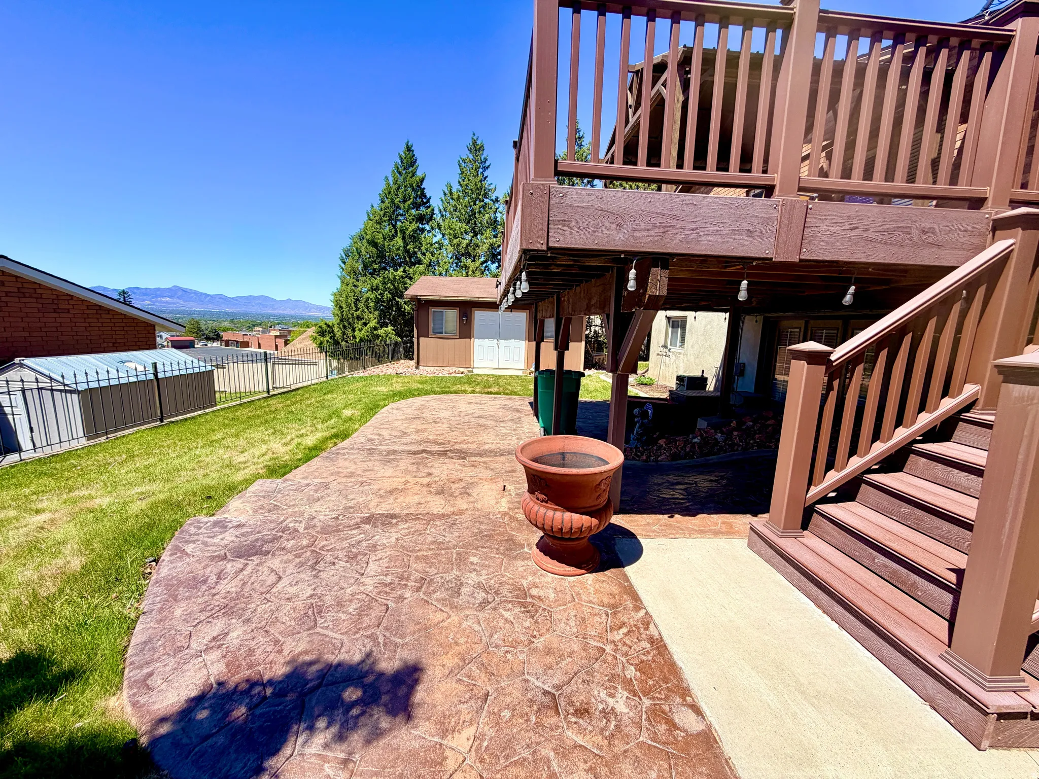 Expansive stamped concrete patio with direct access to an elevated deck featuring a balustrade