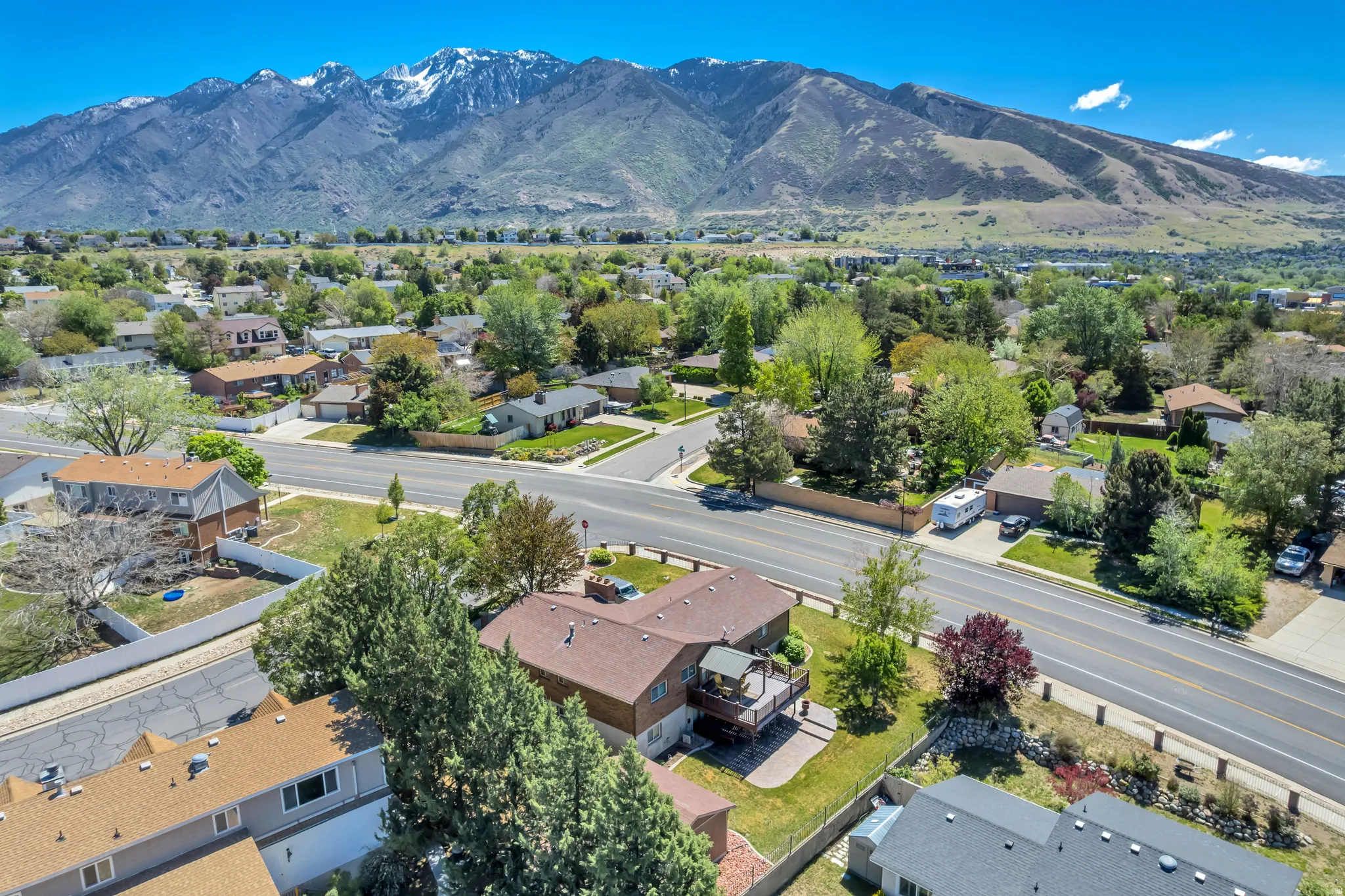Aerial perspective showcasing a residential area with varied housing styles and mature landscaping, set against a backdrop of snow-capped mountains