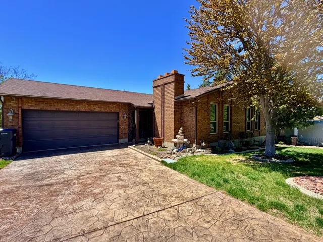 Brick exterior with a prominent chimney feature and a dark brown garage door