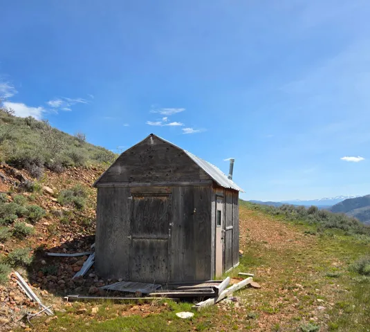Rustic wood-sided structure with a gabled metal roof and a prominent chimney vent