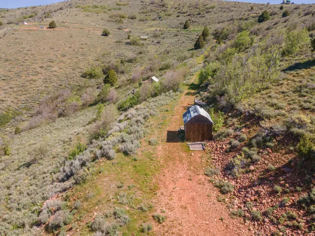 Rustic outbuilding with a metal roof situated on a sloped, natural landscape