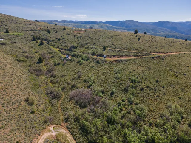 Expansive hillside terrain featuring natural vegetation and distant mountain ranges