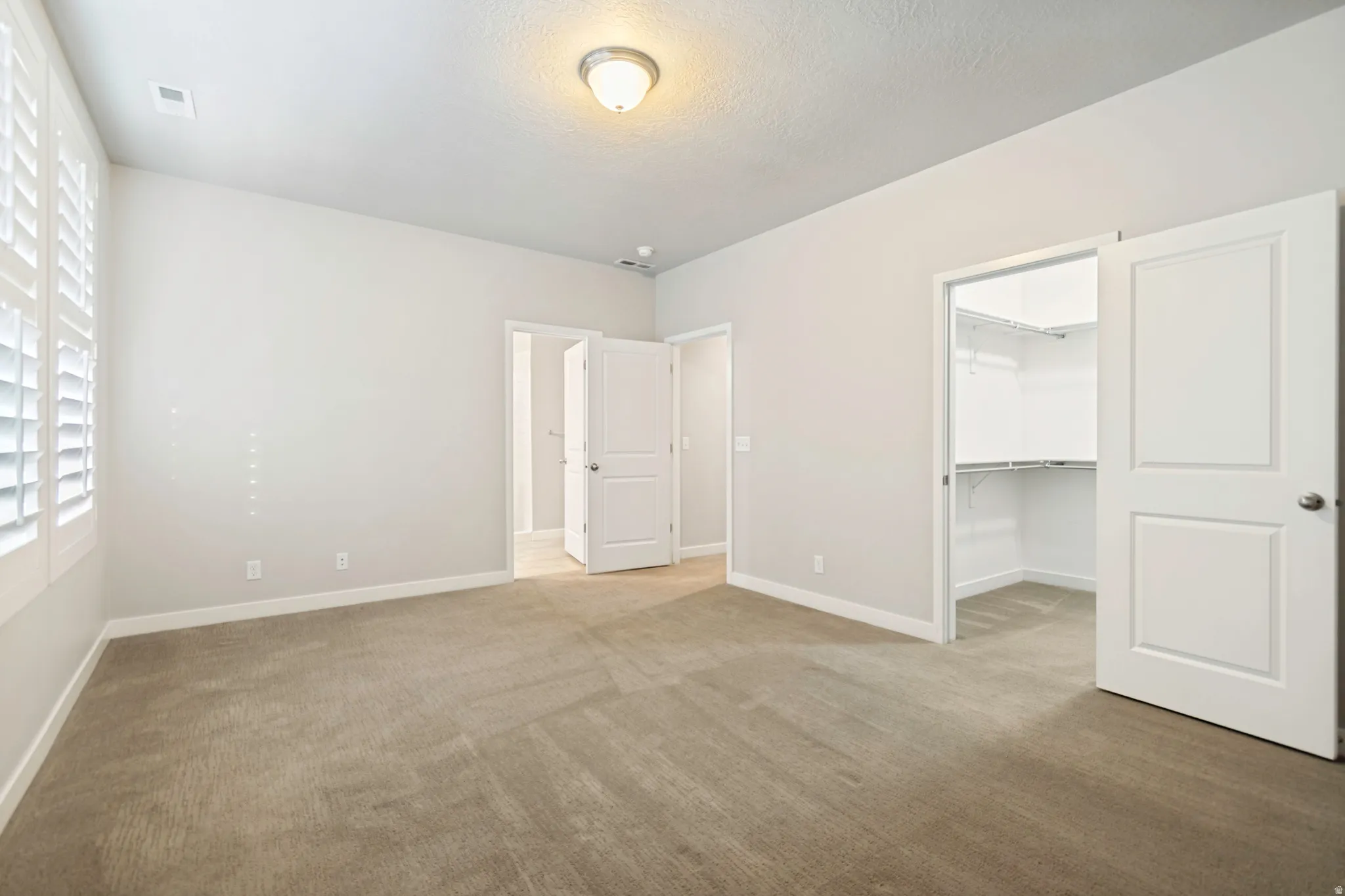 Spacious room featuring neutral carpeting, light-toned walls, and a recessed ceiling light