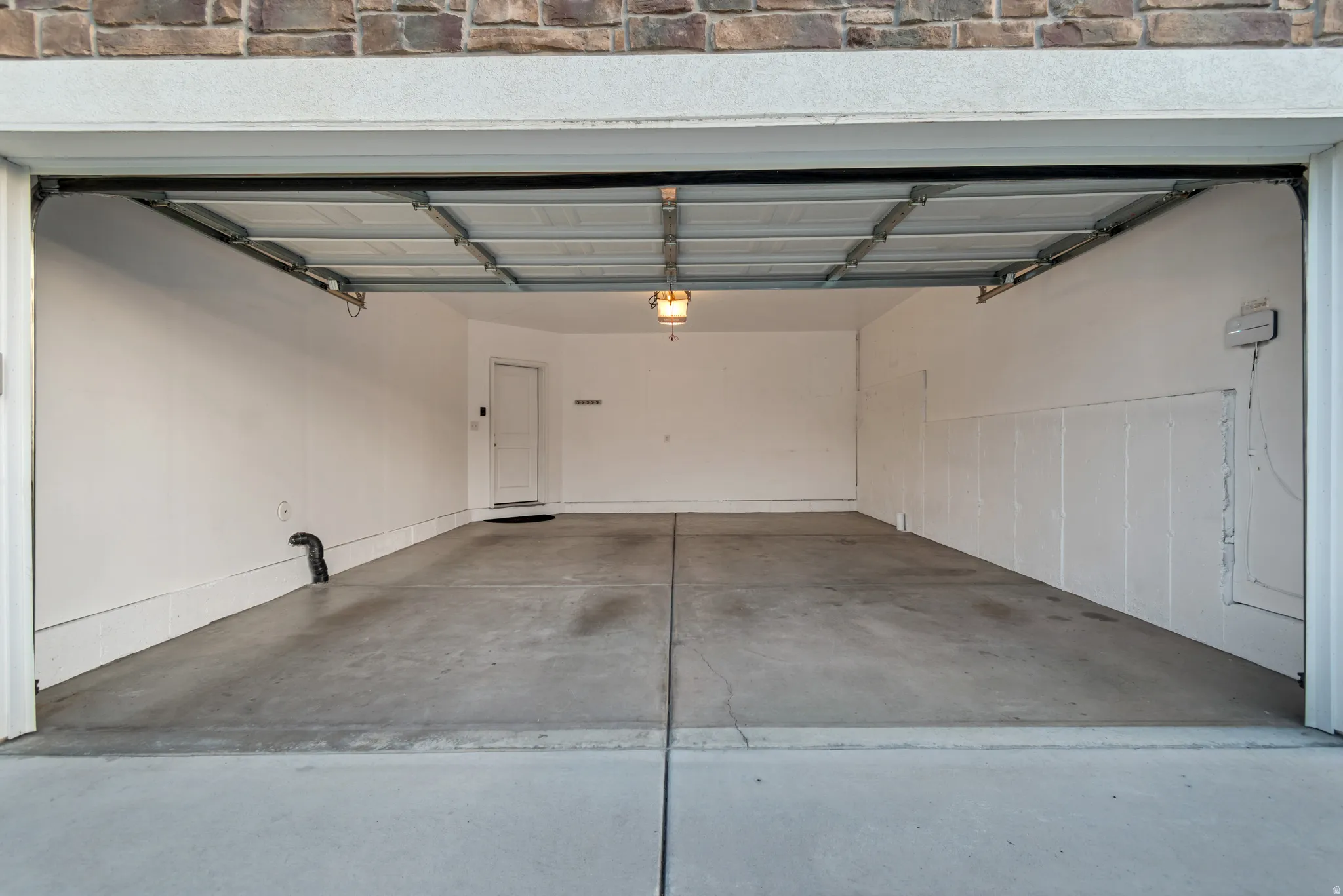 Spacious garage featuring a concrete floor, bright white walls, and an overhead light fixture