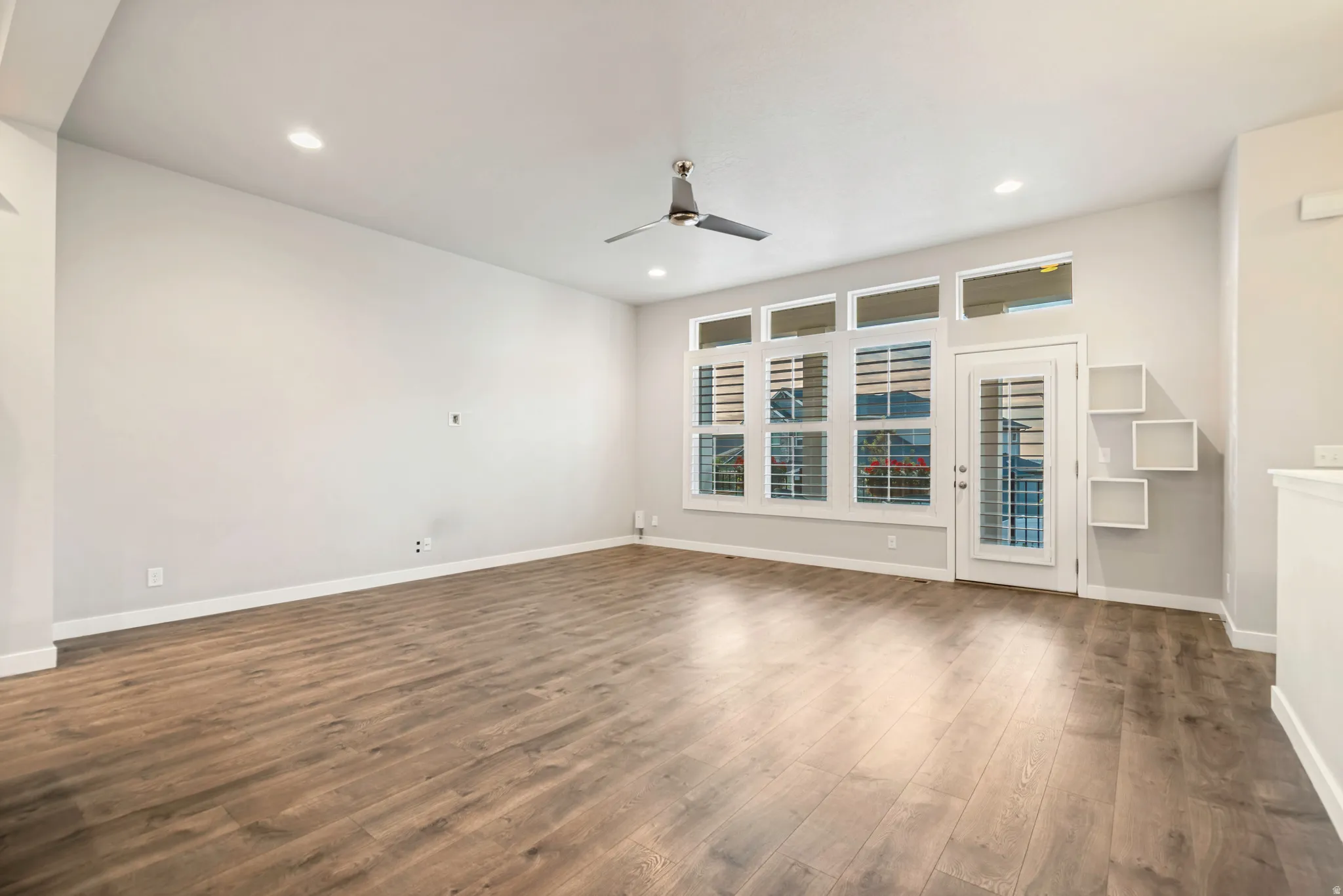Spacious room featuring wood-finish flooring, recessed lighting, and a contemporary ceiling fan