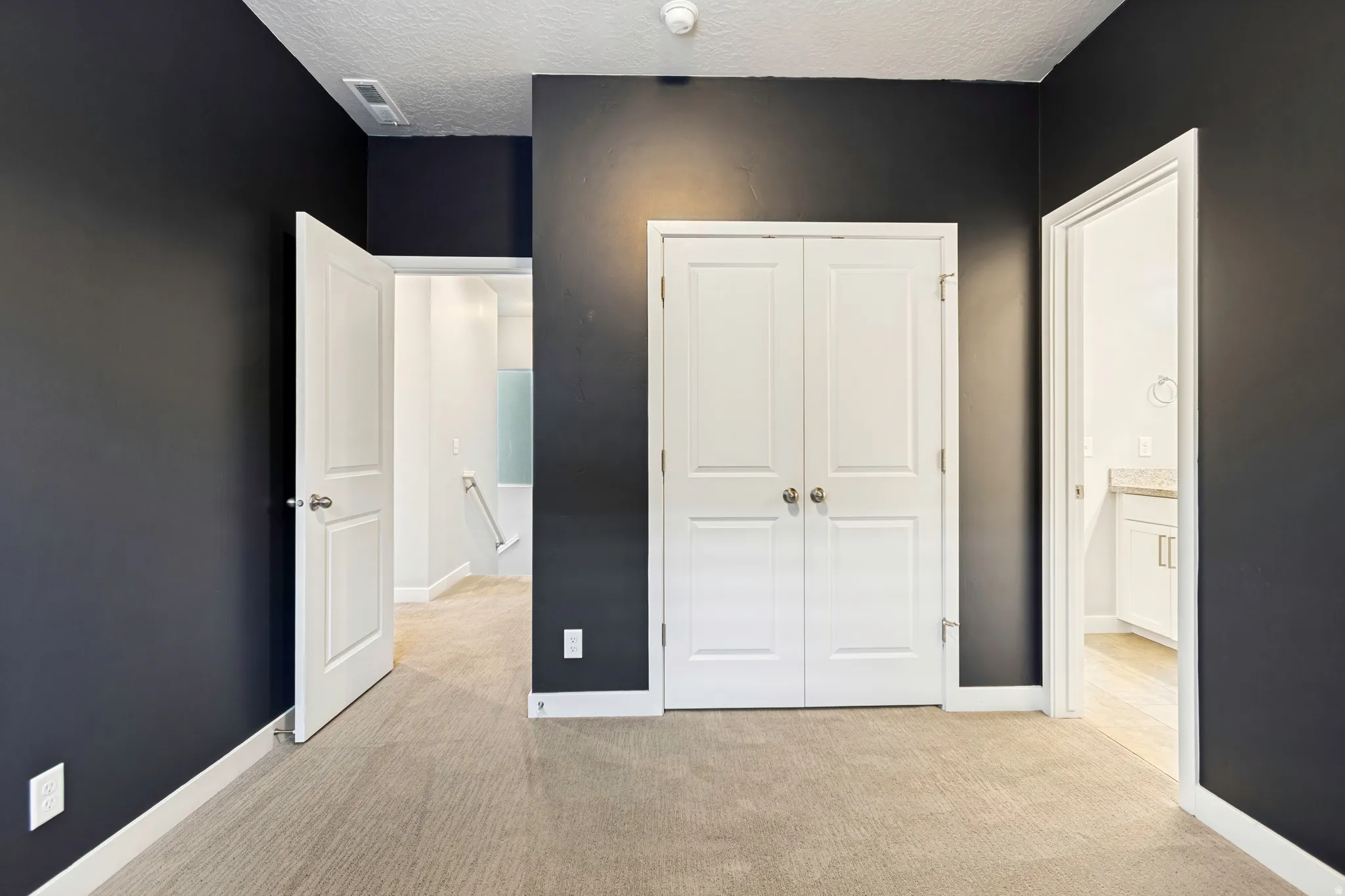 Bedroom featuring dark accent walls, neutral carpet flooring, and white trim