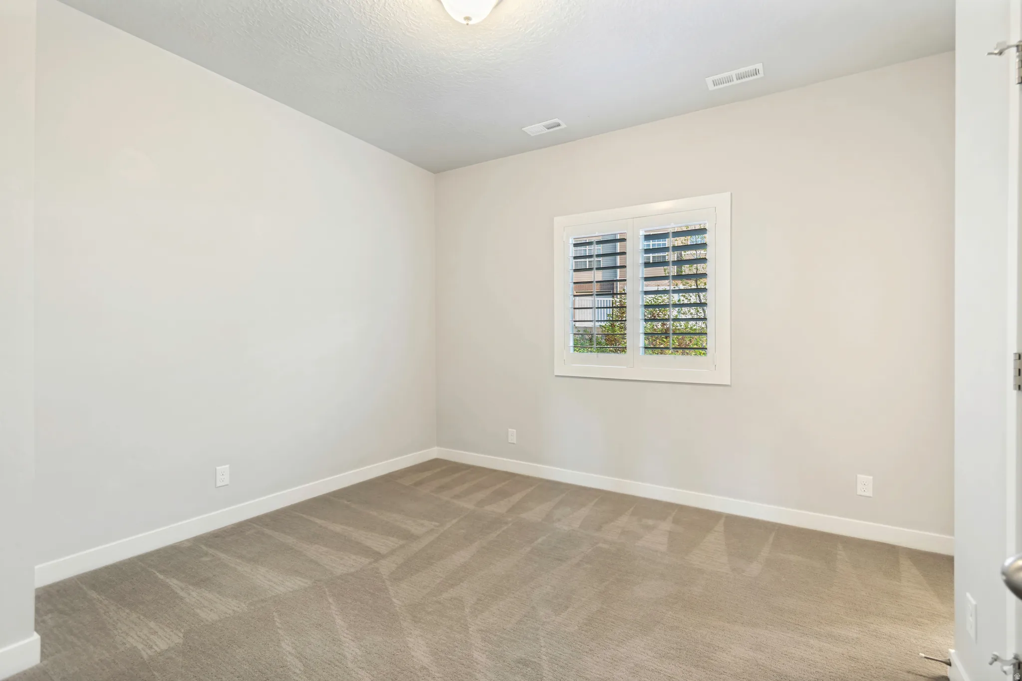 Neutral-toned interior room featuring light gray walls, white baseboards, and patterned gray carpet