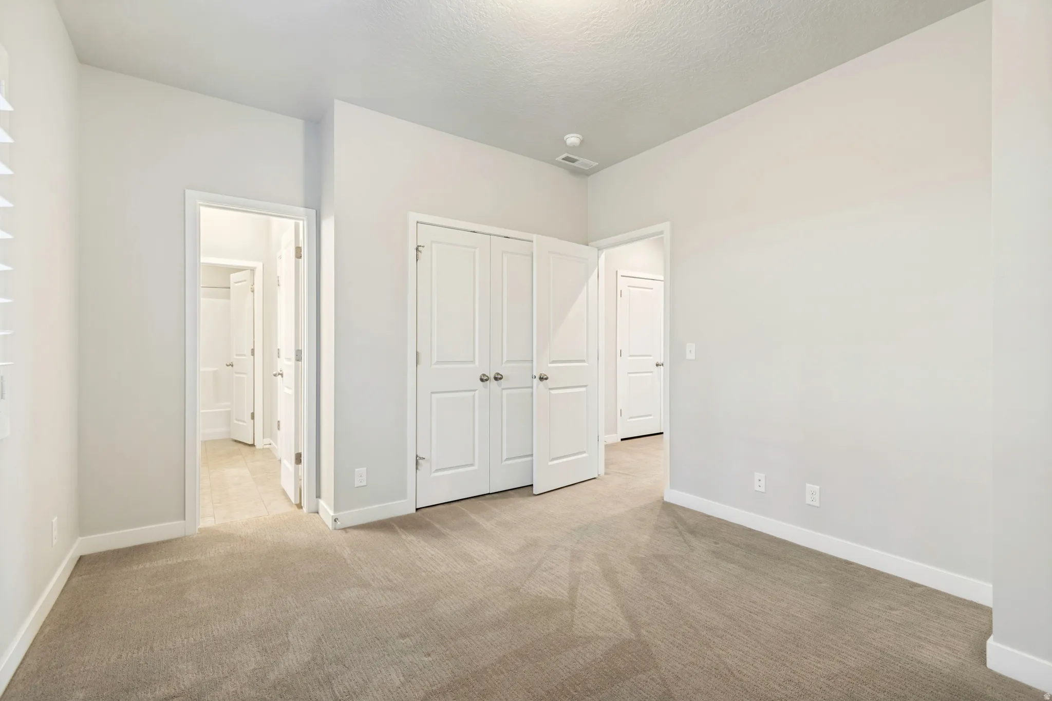 Room featuring light gray walls, neutral carpet flooring, and white baseboards