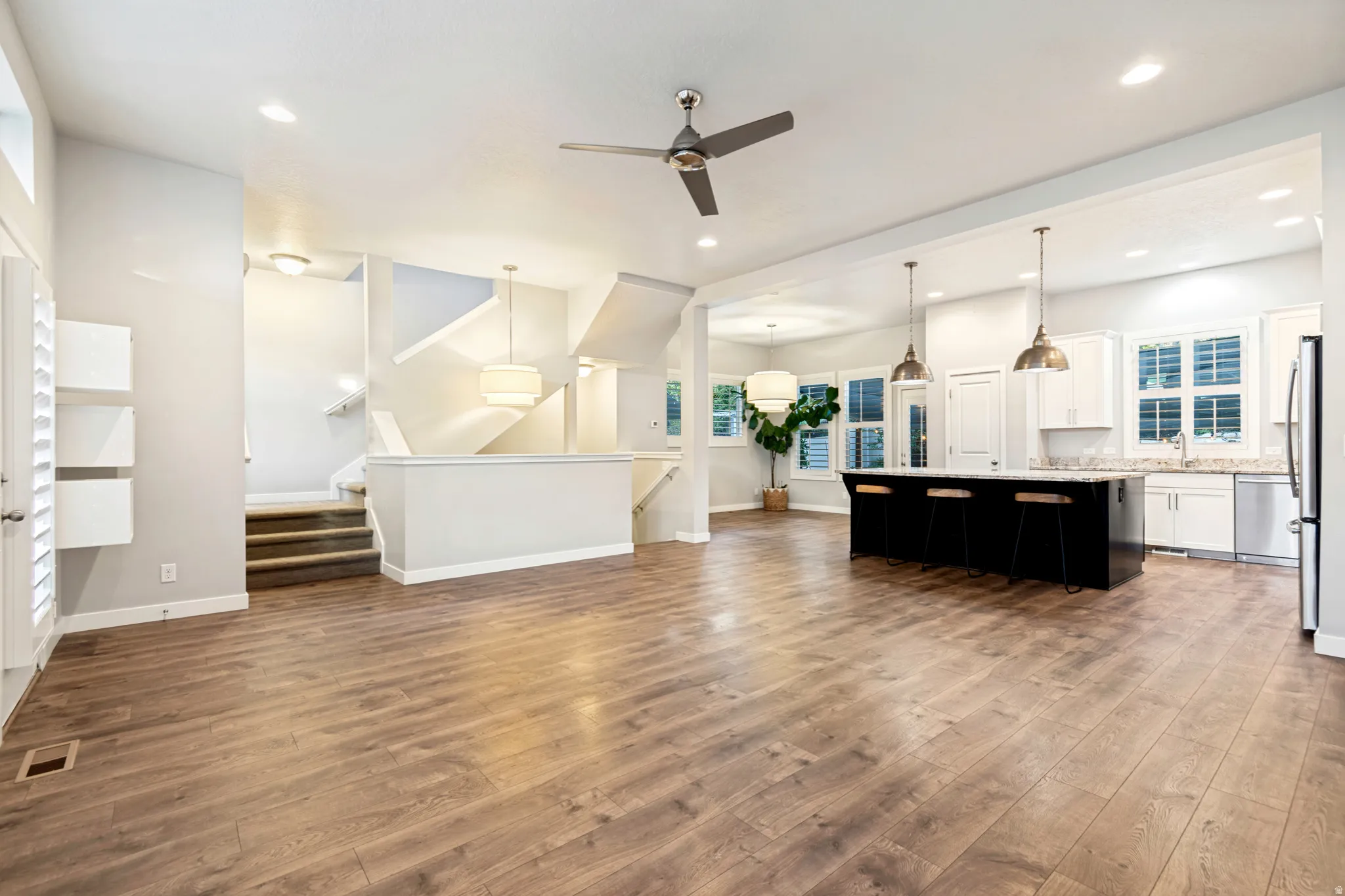 Expansive main living area featuring wood-finish flooring, a contemporary ceiling fan, and recessed lighting