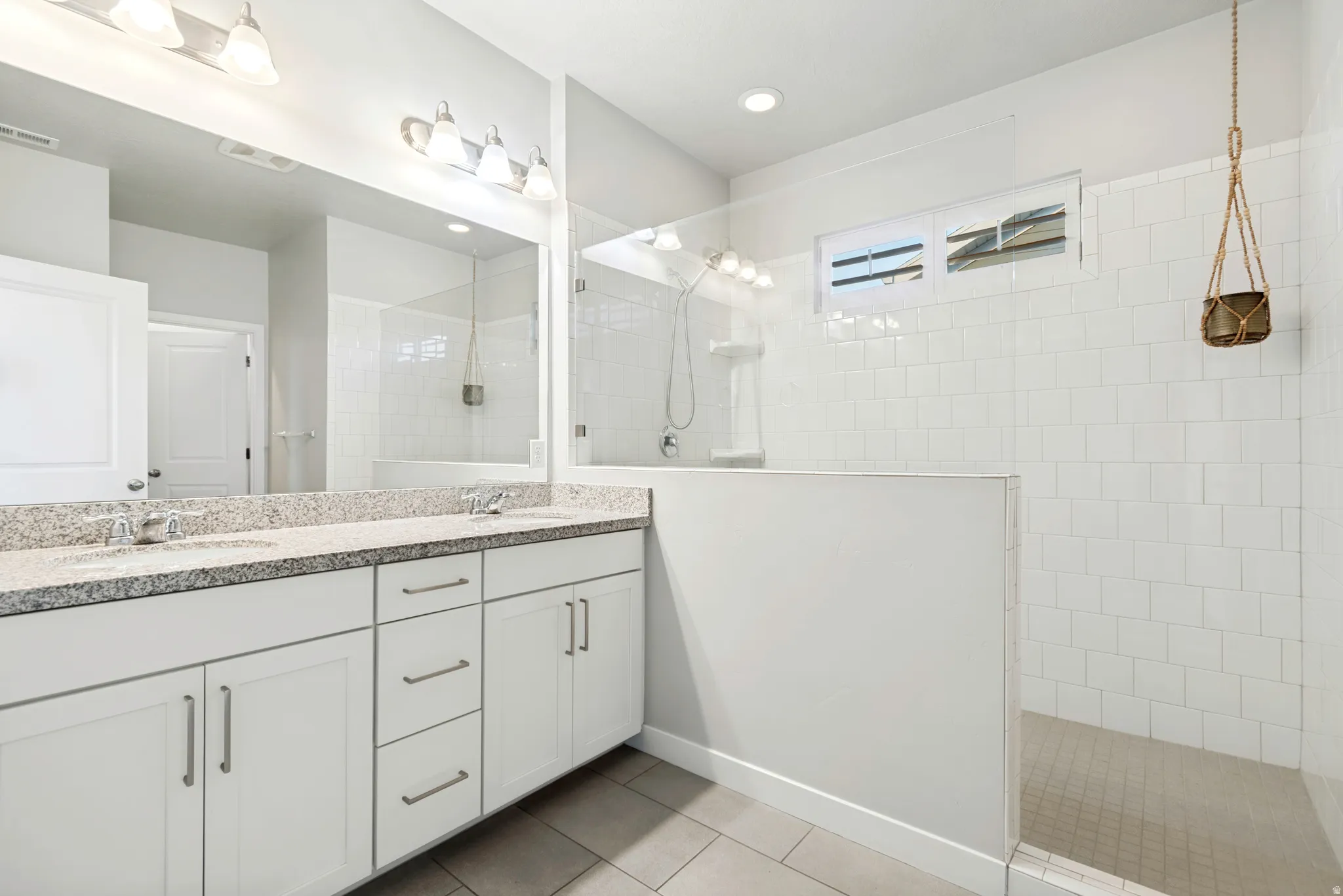 Dual vanity with granite-finish countertop, white cabinetry, and brushed nickel hardware
