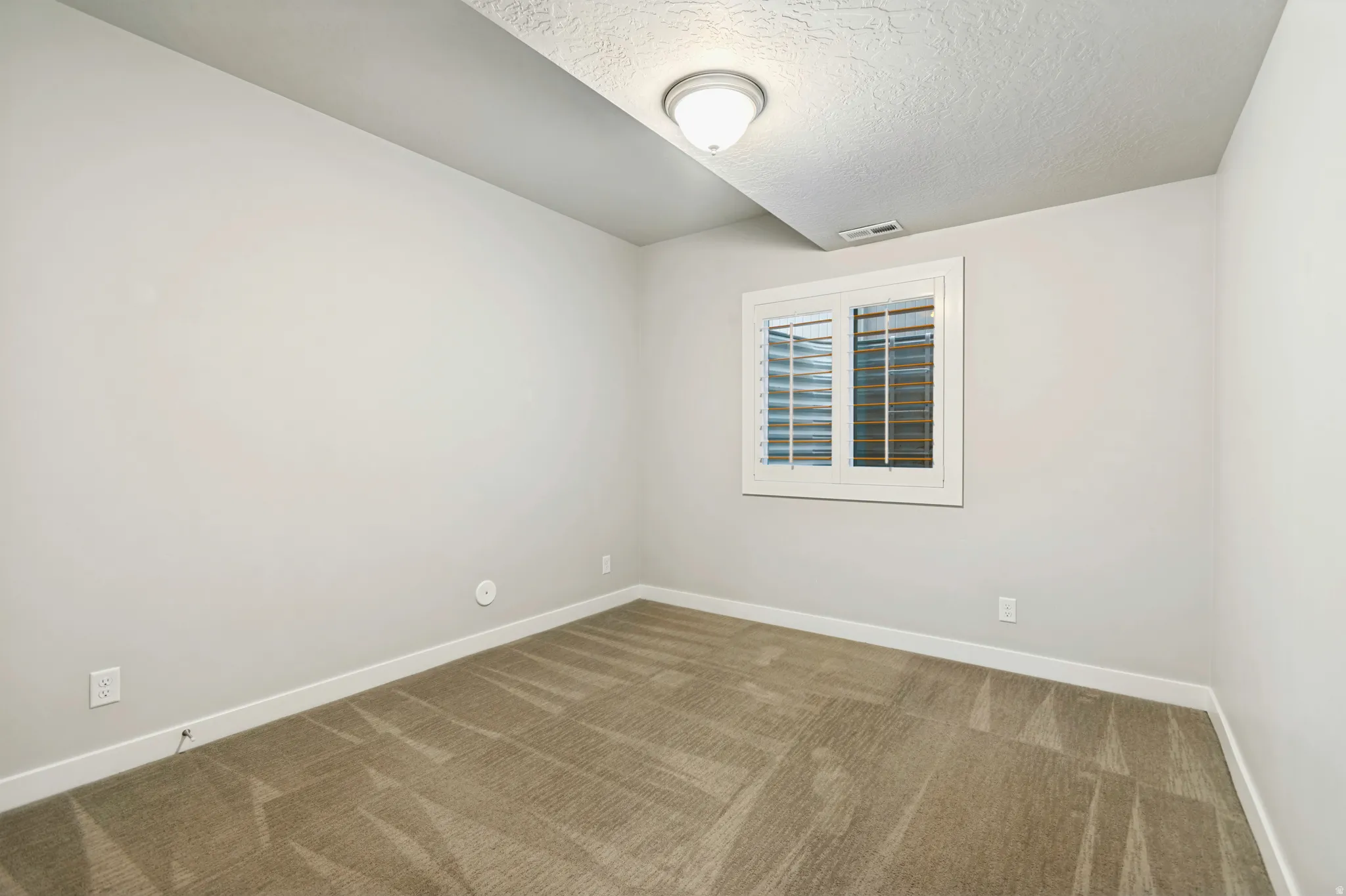 Neutral-toned carpeting, white baseboards, and light gray wall finishes define this room