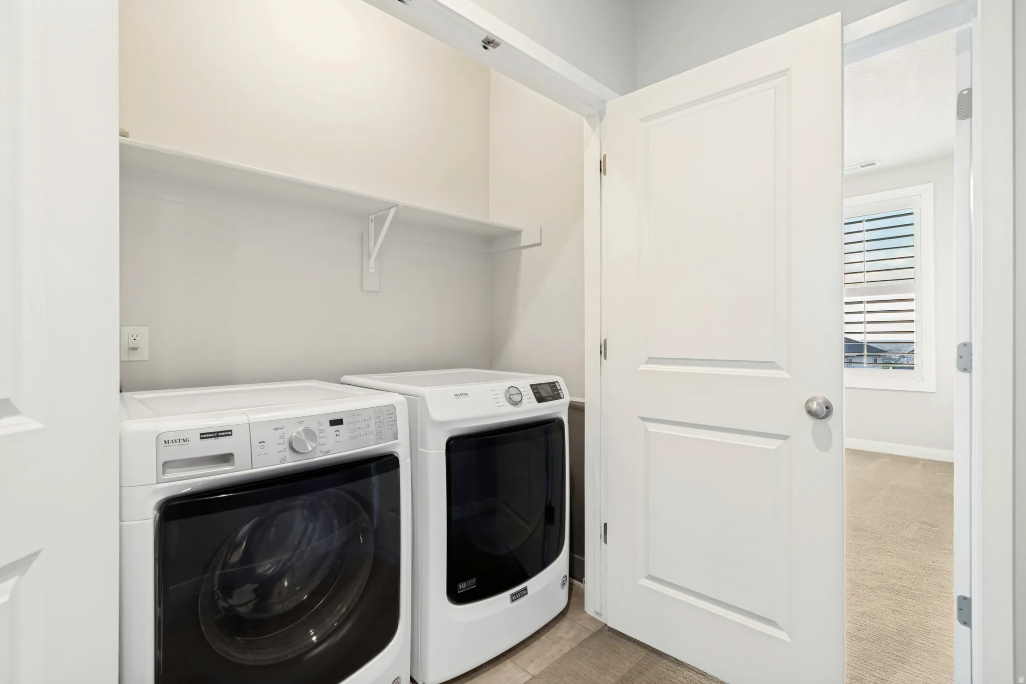Dedicated laundry area featuring a built-in shelving unit, light-toned wall paint, and durable flooring
