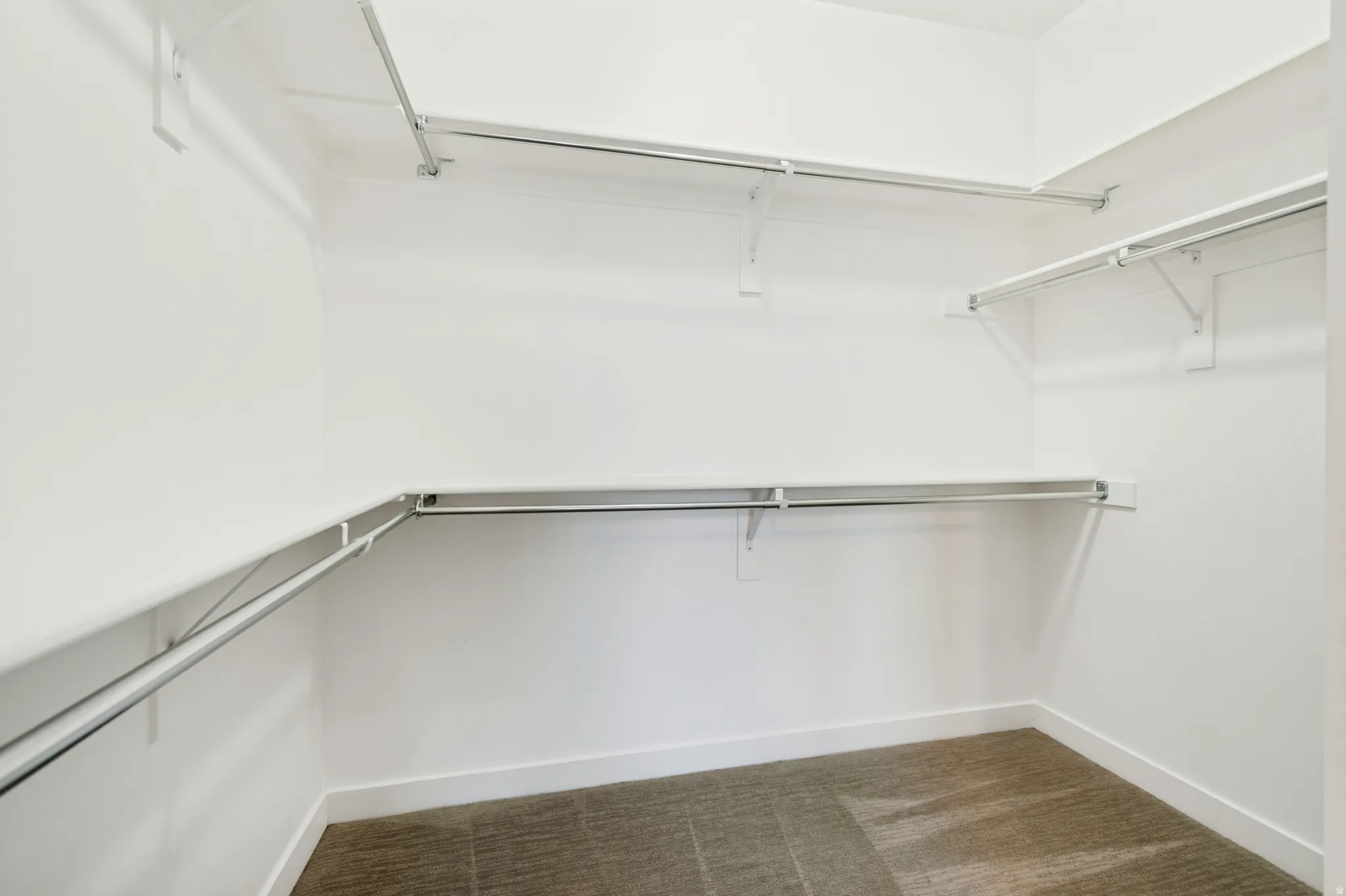 Expansive walk-in closet featuring white walls, white baseboards, and a neutral-toned carpet
