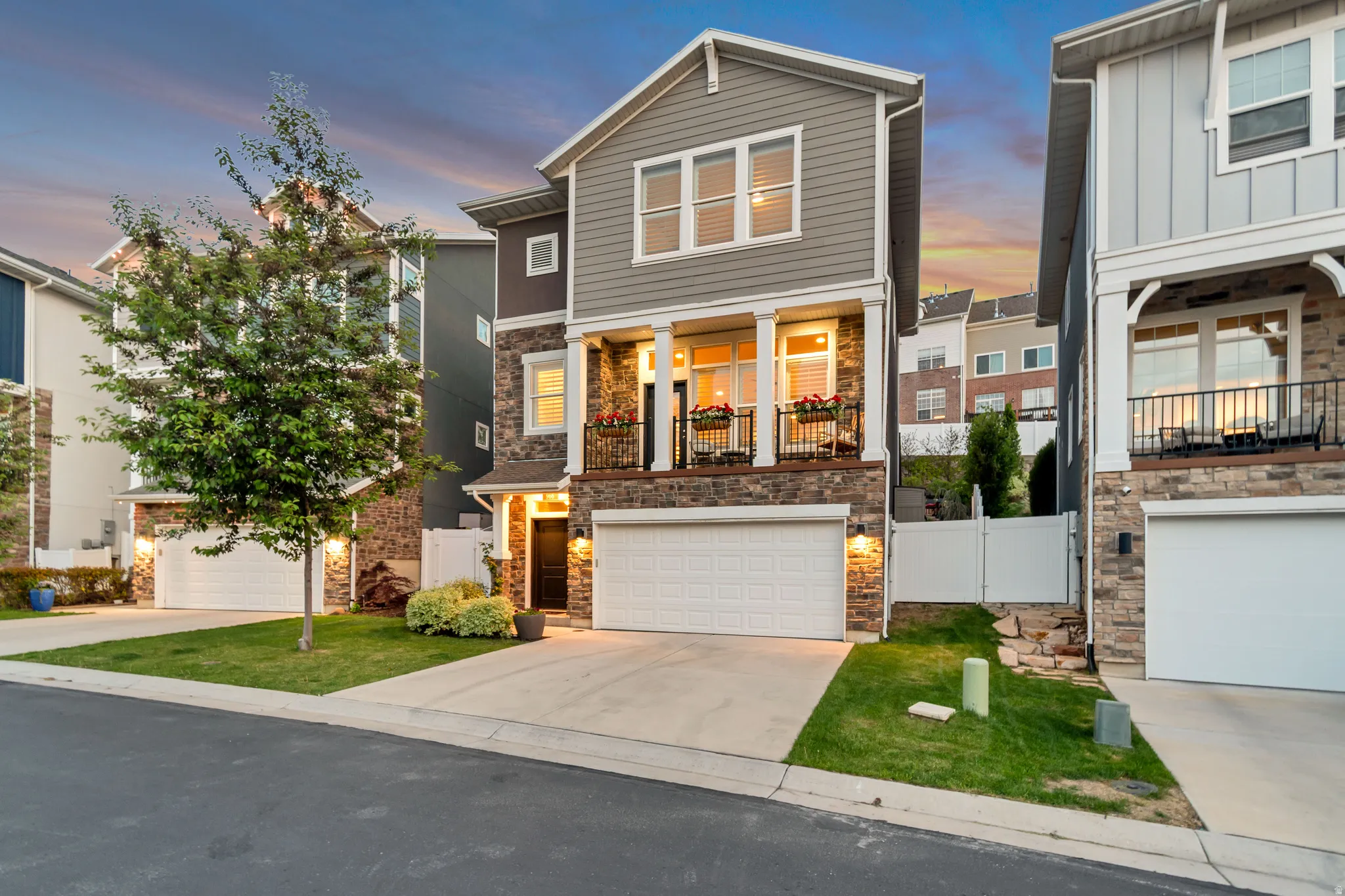 Multi-level residence featuring stone and horizontal siding, a two-car garage, and a covered entryway