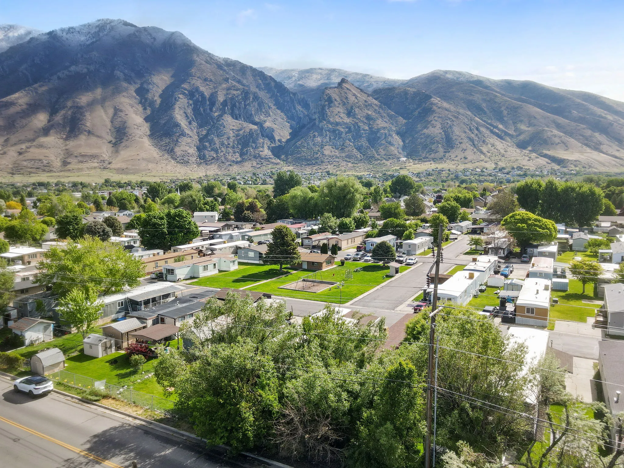 Aerial perspective showcasing the community playground across the street from the home, surrounded by mountainous terrain