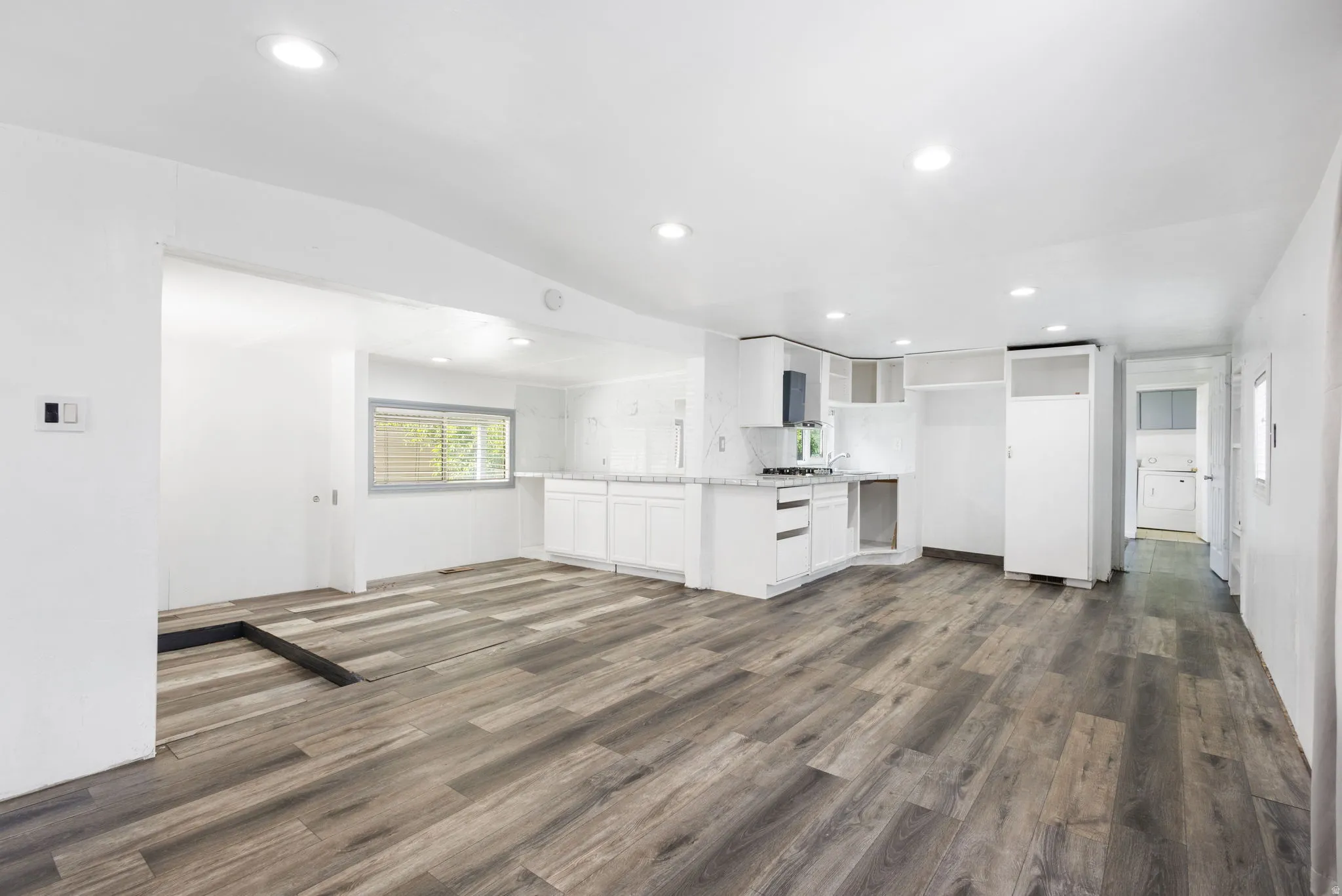 Open-concept living space featuring LVP flooring, recessed lighting, and white walls