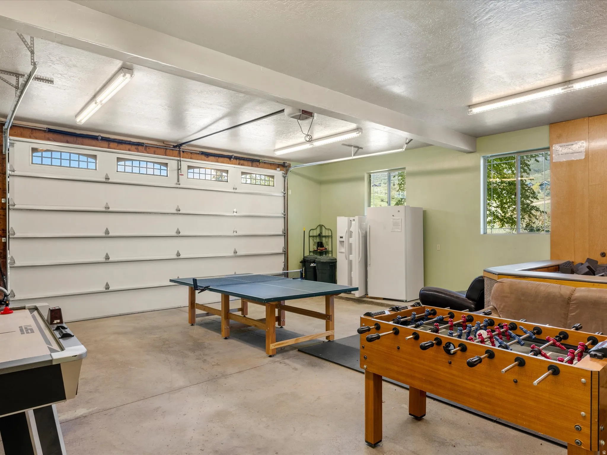 Versatile garage space featuring a concrete floor, multiple windows, and overhead strip lighting