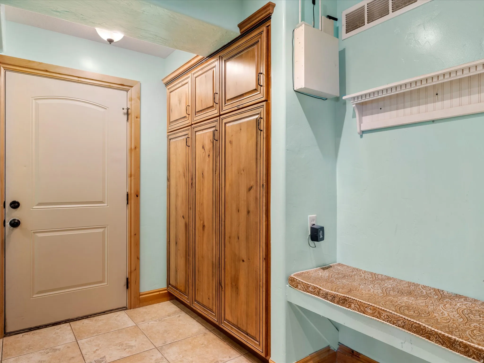 Entryway to sunroom featuring tile flooring, a built-in storage bench, and extensive wood cabinetry