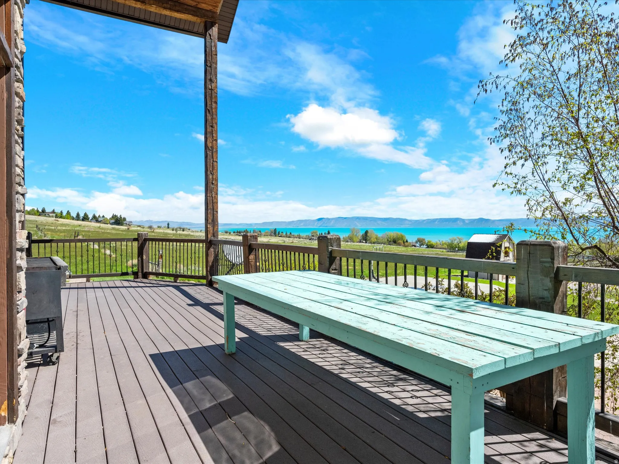 Expansive outdoor deck featuring wood-finish flooring, a sturdy railing, and a stone-clad exterior wall