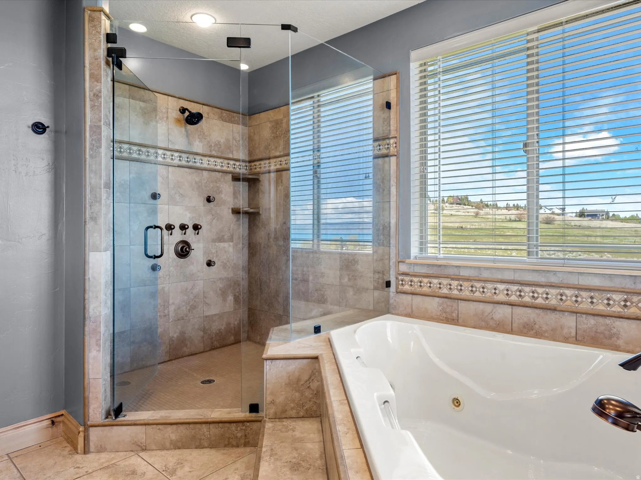Tiled walk-in shower with glass enclosure and multiple sprayers