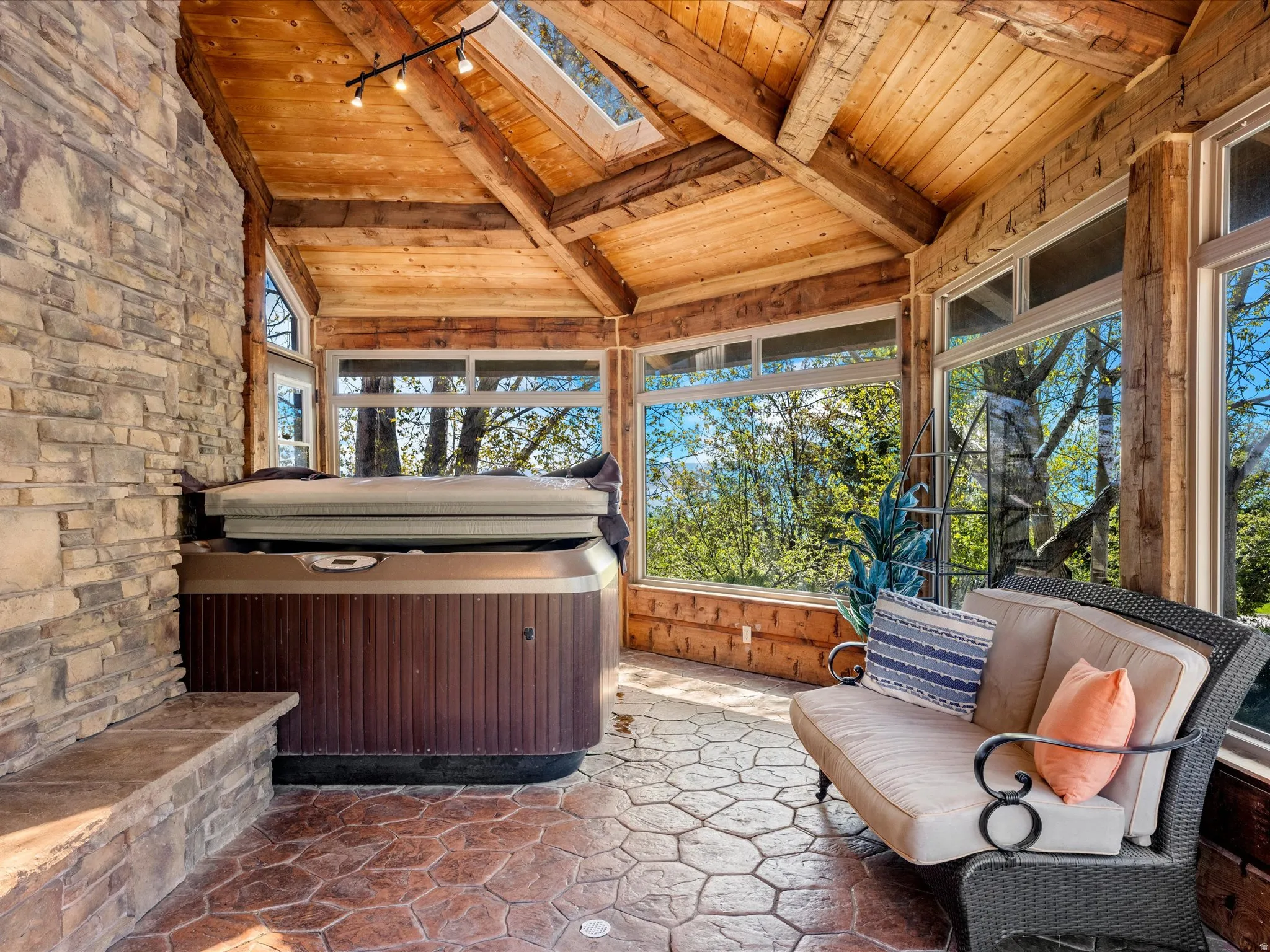 Sunroom featuring a hot tub, stone wall, vaulted wood-plank ceiling, and stamped concrete flooring