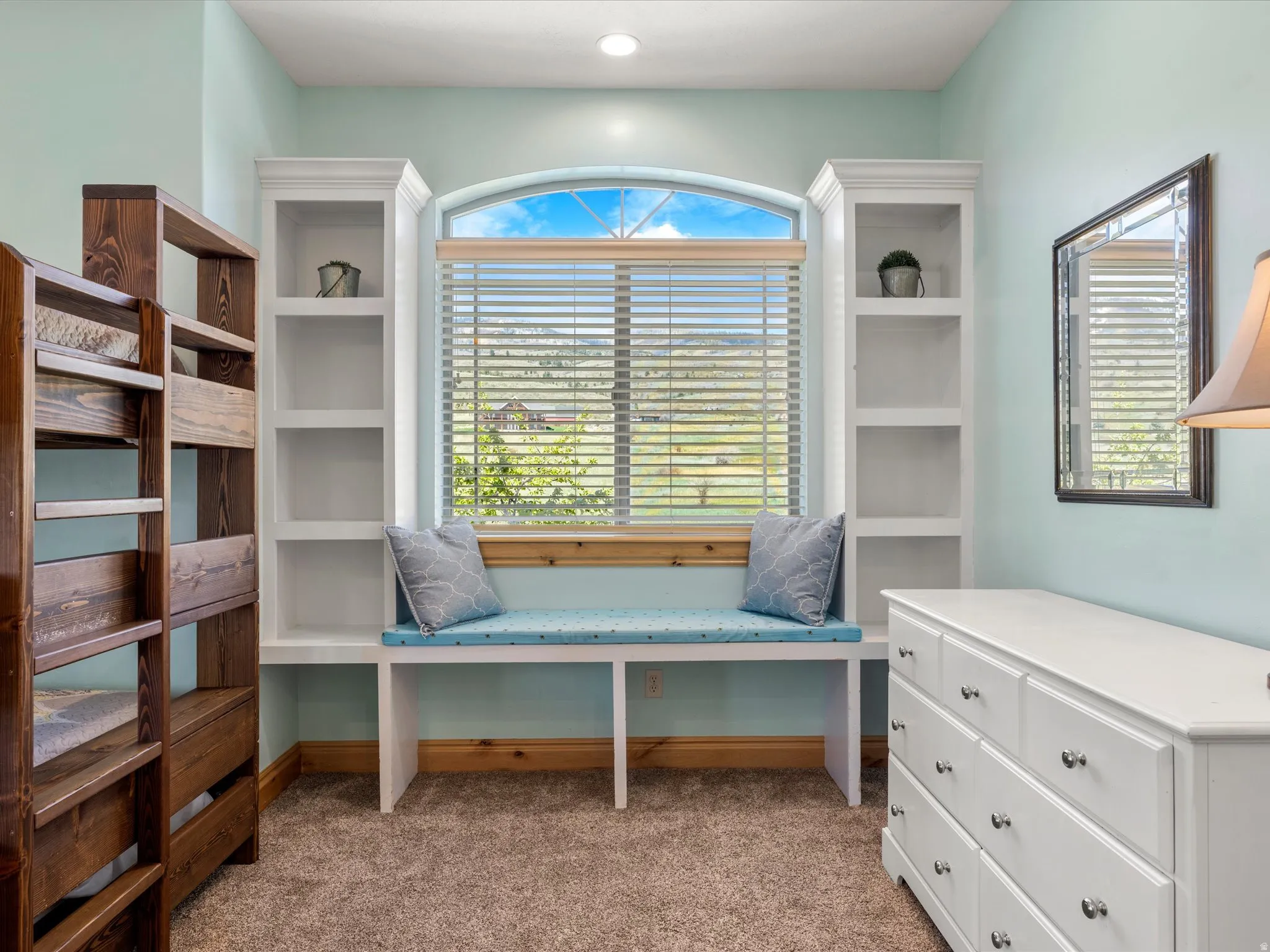 Built-in window seat with an arched window, flanked by custom white cabinetry