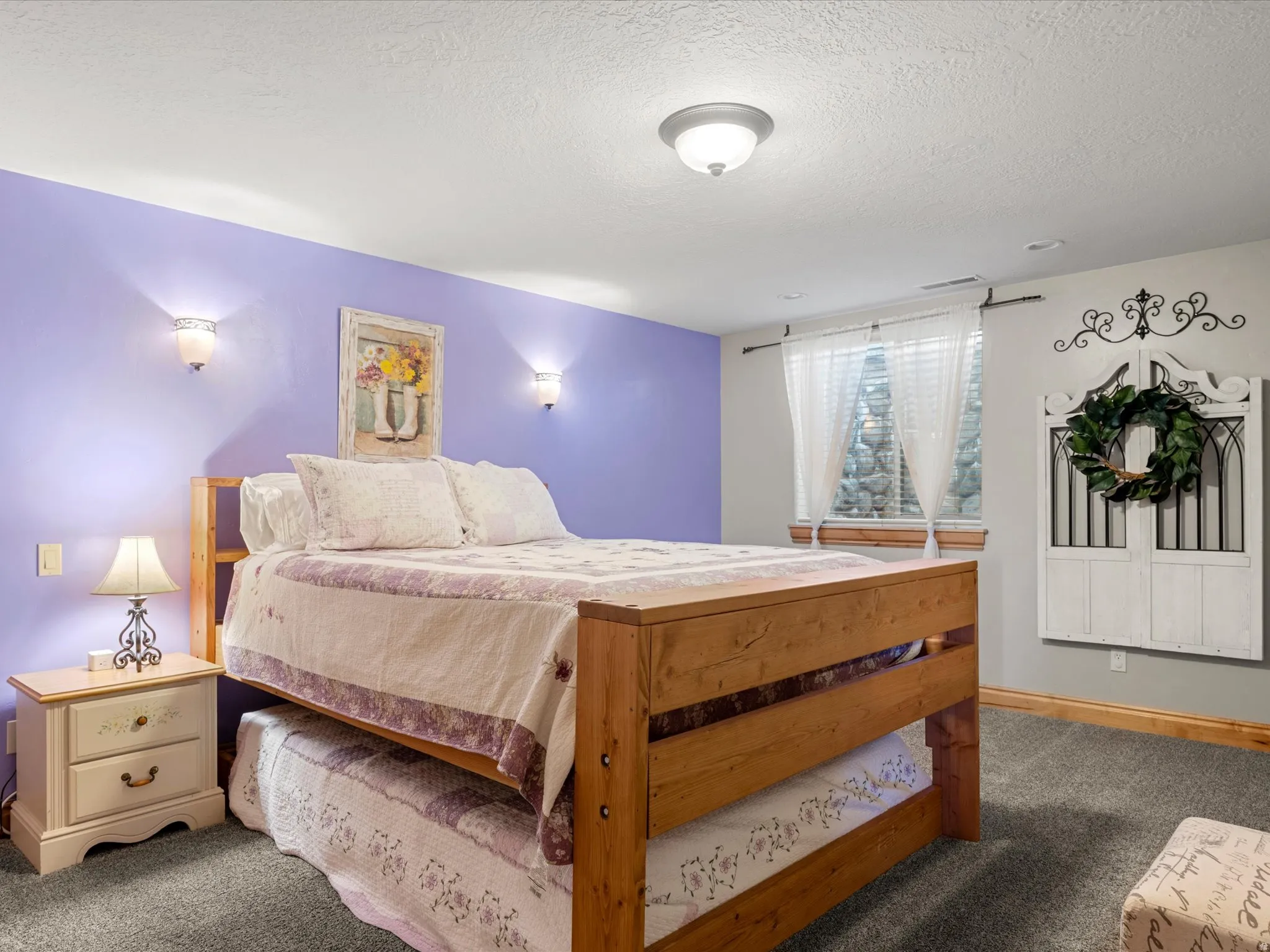 Bedroom featuring a wood-finish trundle bed, purple and grey wall tones, and carpet flooring