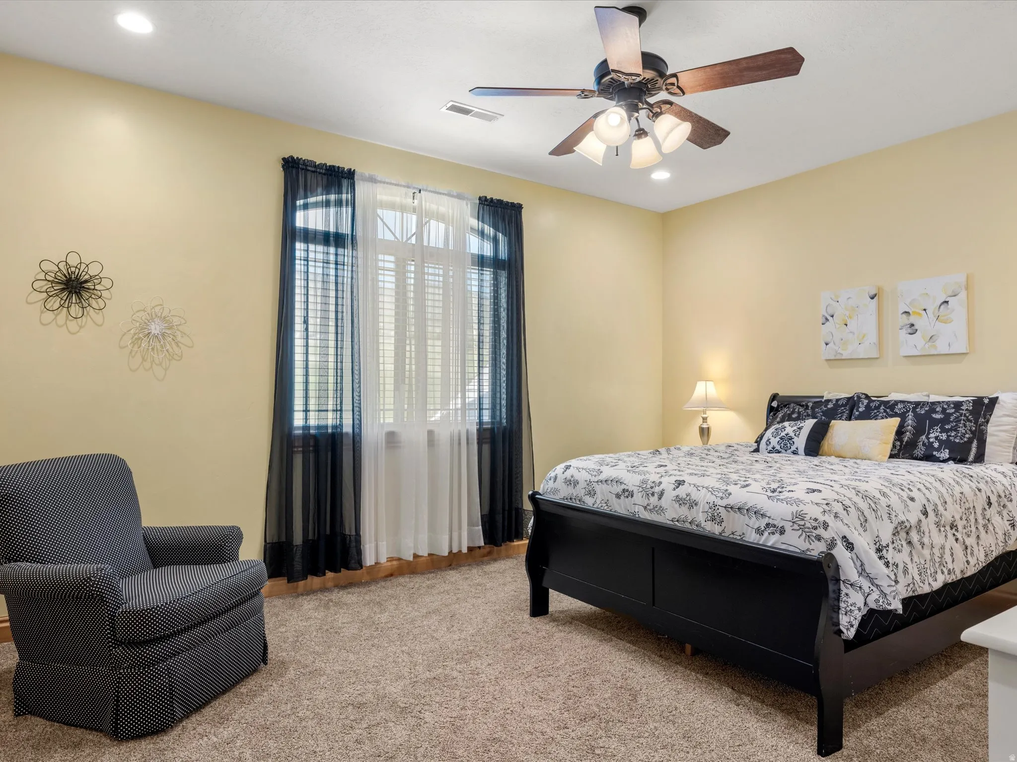 Neutral-toned walls and plush carpeting complement the ceiling fan with integrated lighting
