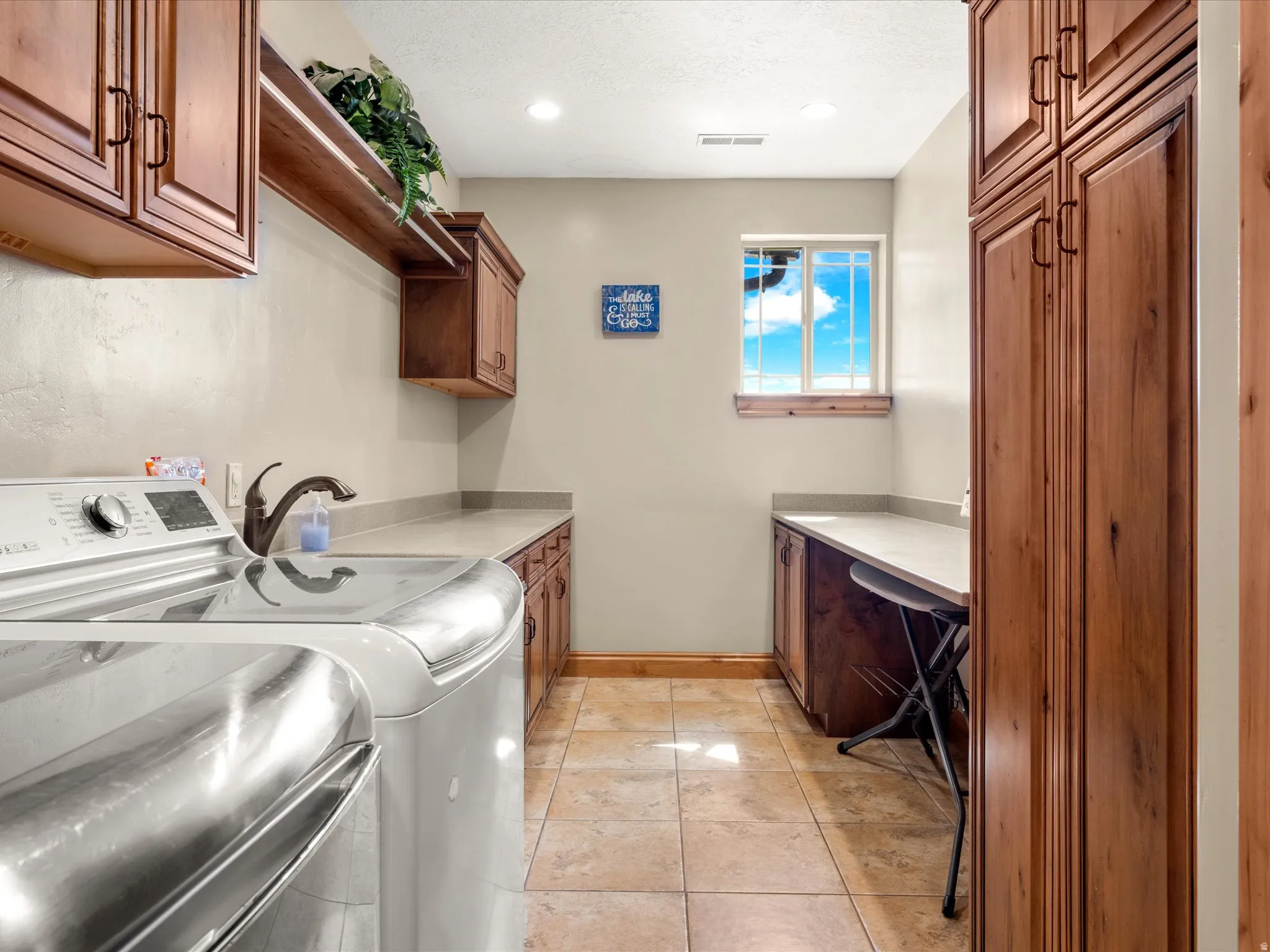 2nd floor Laundry area with extensive wood cabinetry, light-toned countertops, and tile flooring