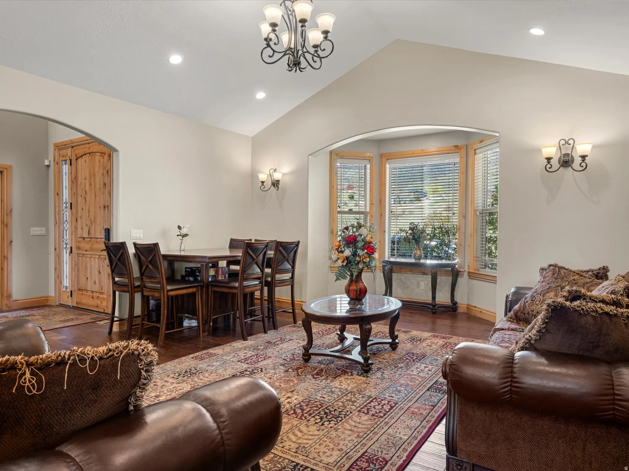 Vaulted living area featuring wood-finish flooring, recessed lighting, and an arched entryway