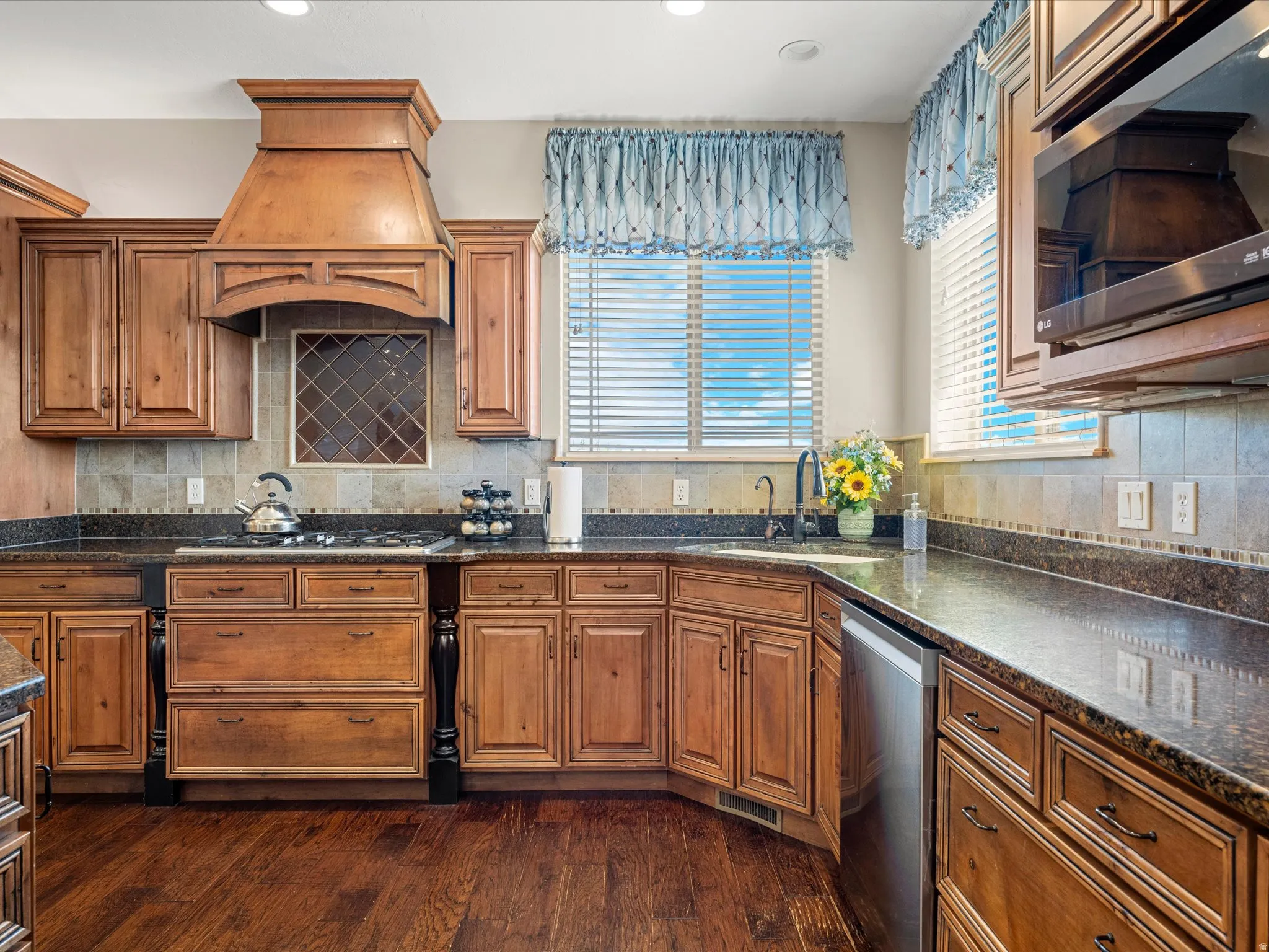 Kitchen featuring wood-finish cabinetry, dark granite countertops, and a tile backsplash