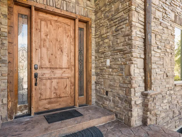 Solid wood entry door with decorative glass sidelights, set within a stone-clad exterior