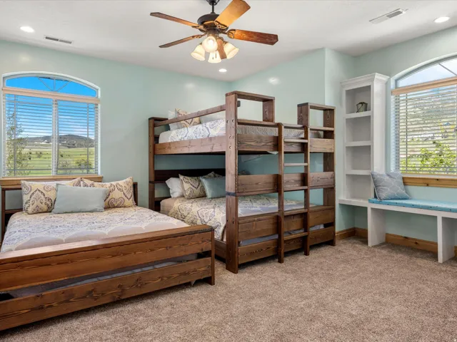 Spacious room featuring multiple beds, a built-in window seat, integrated shelving, and a ceiling fan
