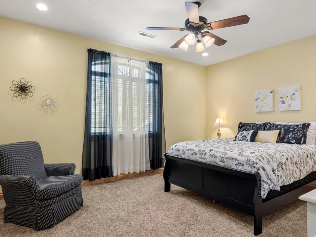 Neutral-toned walls and plush carpeting complement the ceiling fan with integrated lighting