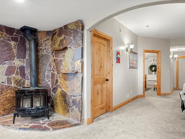 Stone accent wall featuring a black wood-burning stove with a metal flue