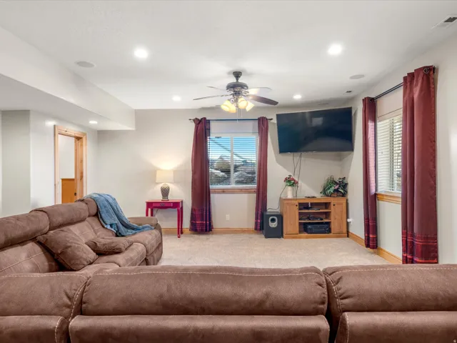 Carpeted entertainment area featuring recessed lighting, a ceiling fan, and two windows with blinds and curtain rods