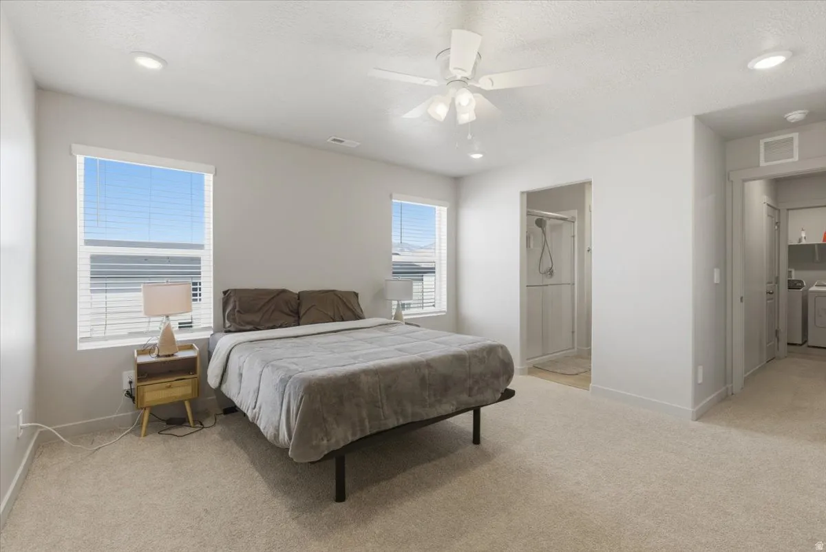 Spacious carpeted room featuring two windows, recessed lighting, and a ceiling fan