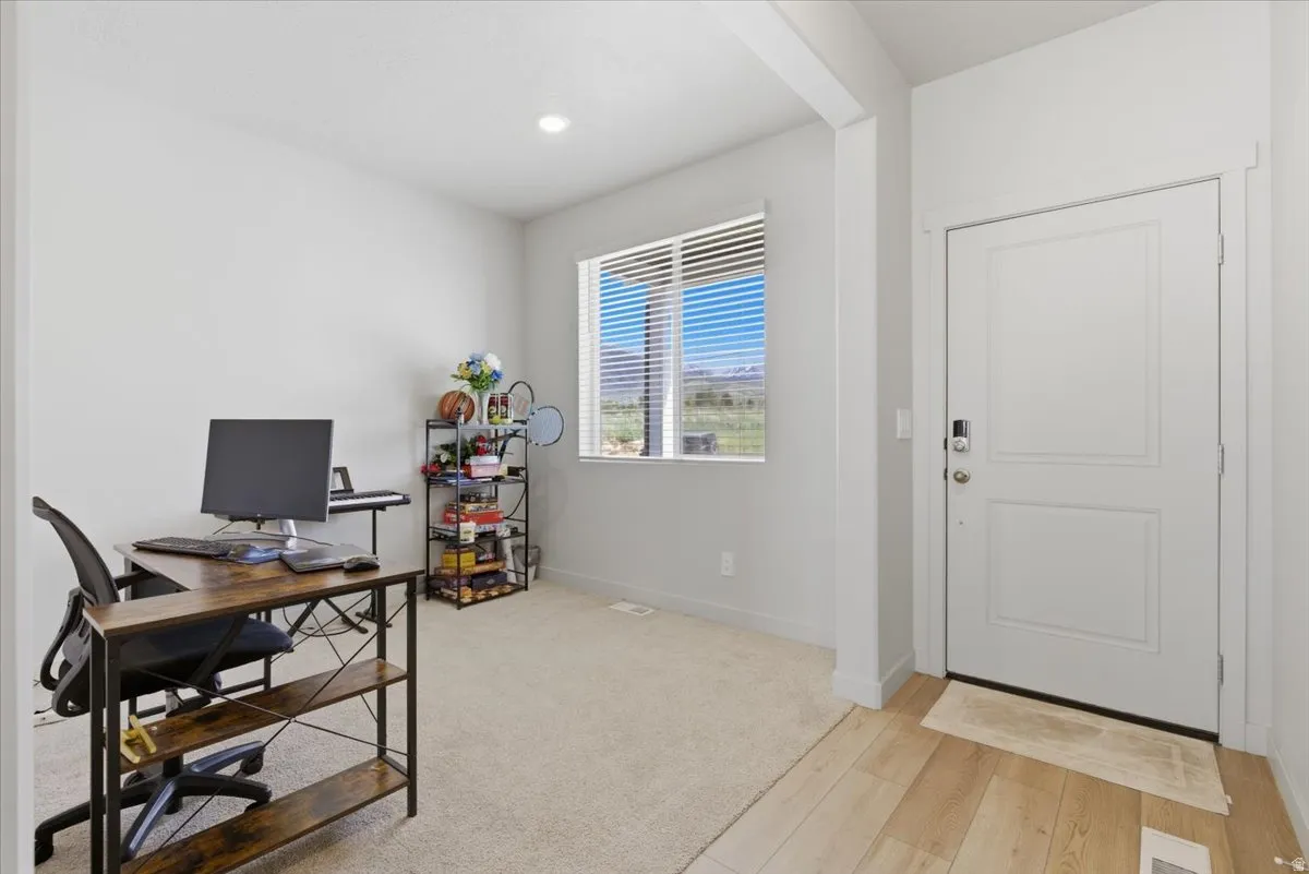 Entryway office featuring light wood-finish flooring, a white two-panel door, recessed lighting, and a window with horizontal blinds