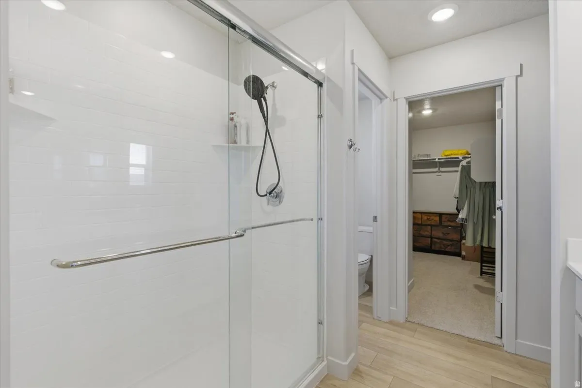 Glass-enclosed shower with white subway tile surround, integrated shelving, and a dark-finish showerhead