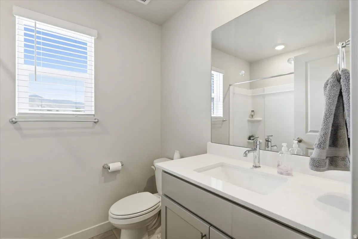 Bathroom featuring a single vanity with an integrated rectangular sink, a light-toned countertop, and chrome fixtures