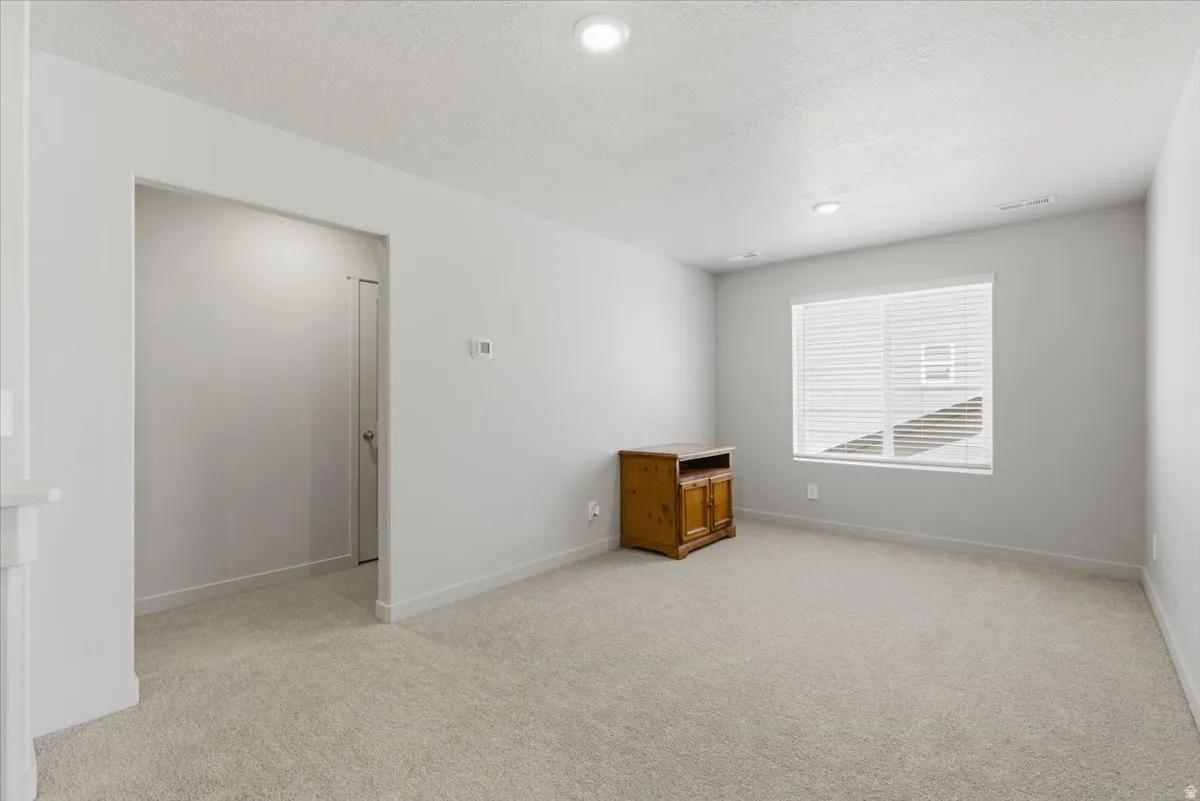 Spacious room featuring neutral carpeting, light gray wall paint, and white trim
