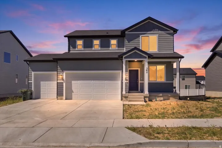 Two-story residence featuring a covered entry, dark blue door, and two-car garage