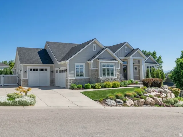 Contemporary residence featuring a light gray siding exterior with stone accents, multiple gables, and a prominent front entrance with white columns