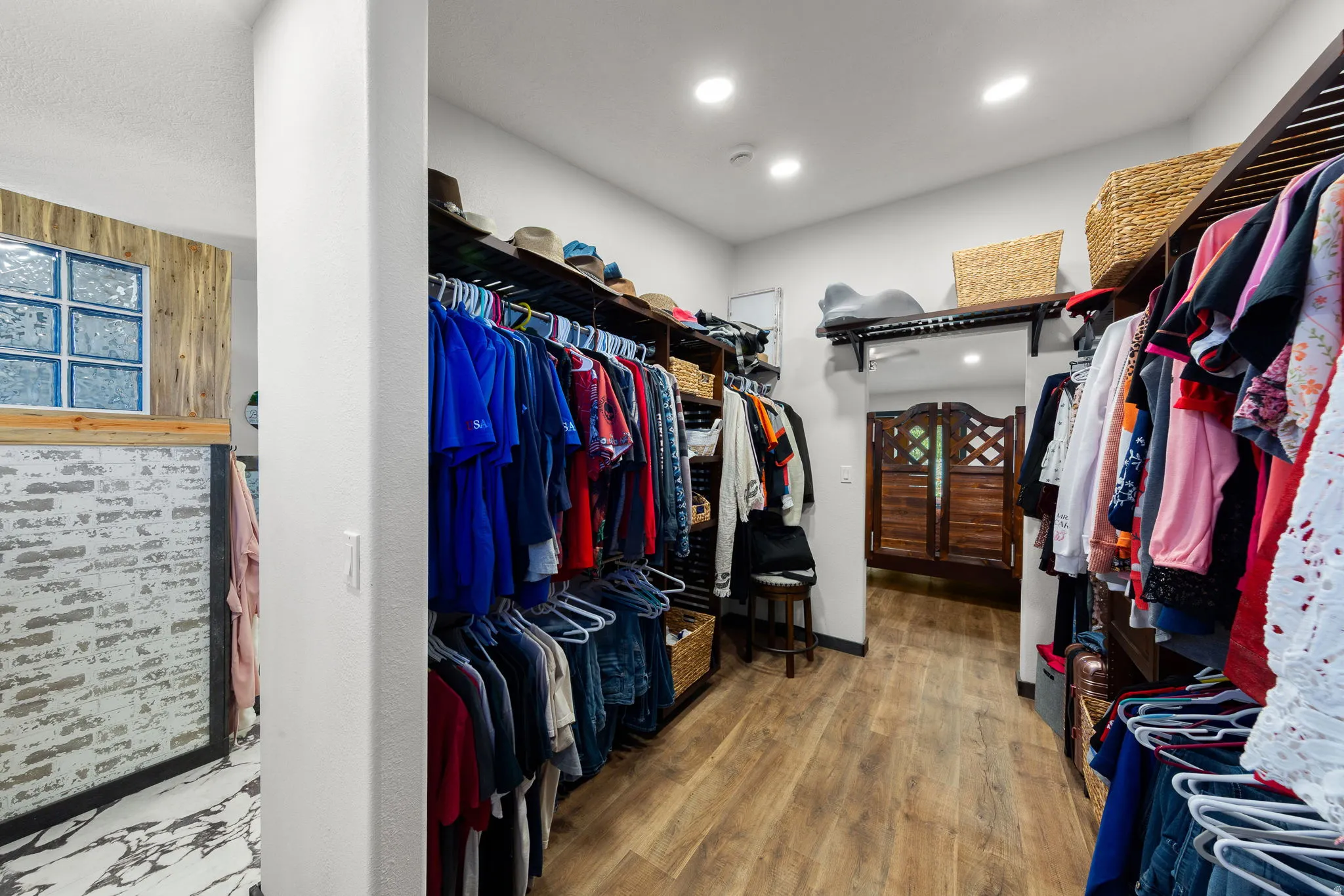 Expansive custom closet featuring wood-finish flooring, recessed lighting, and built-in shelving