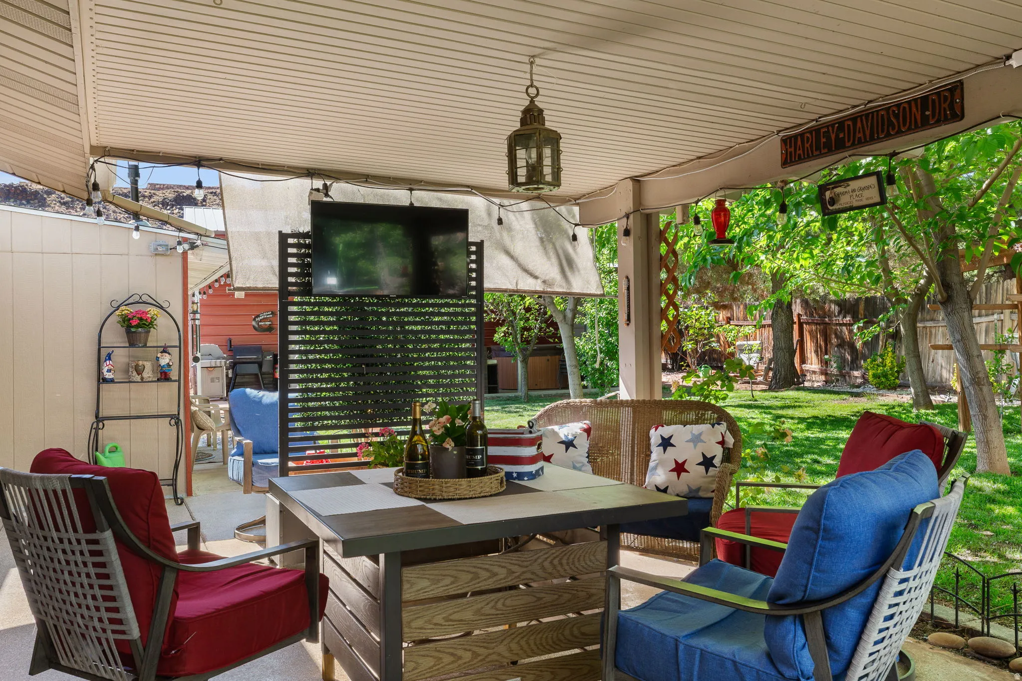Covered patio featuring an outdoor television, a decorative privacy screen, and an overhead lantern-style light fixture