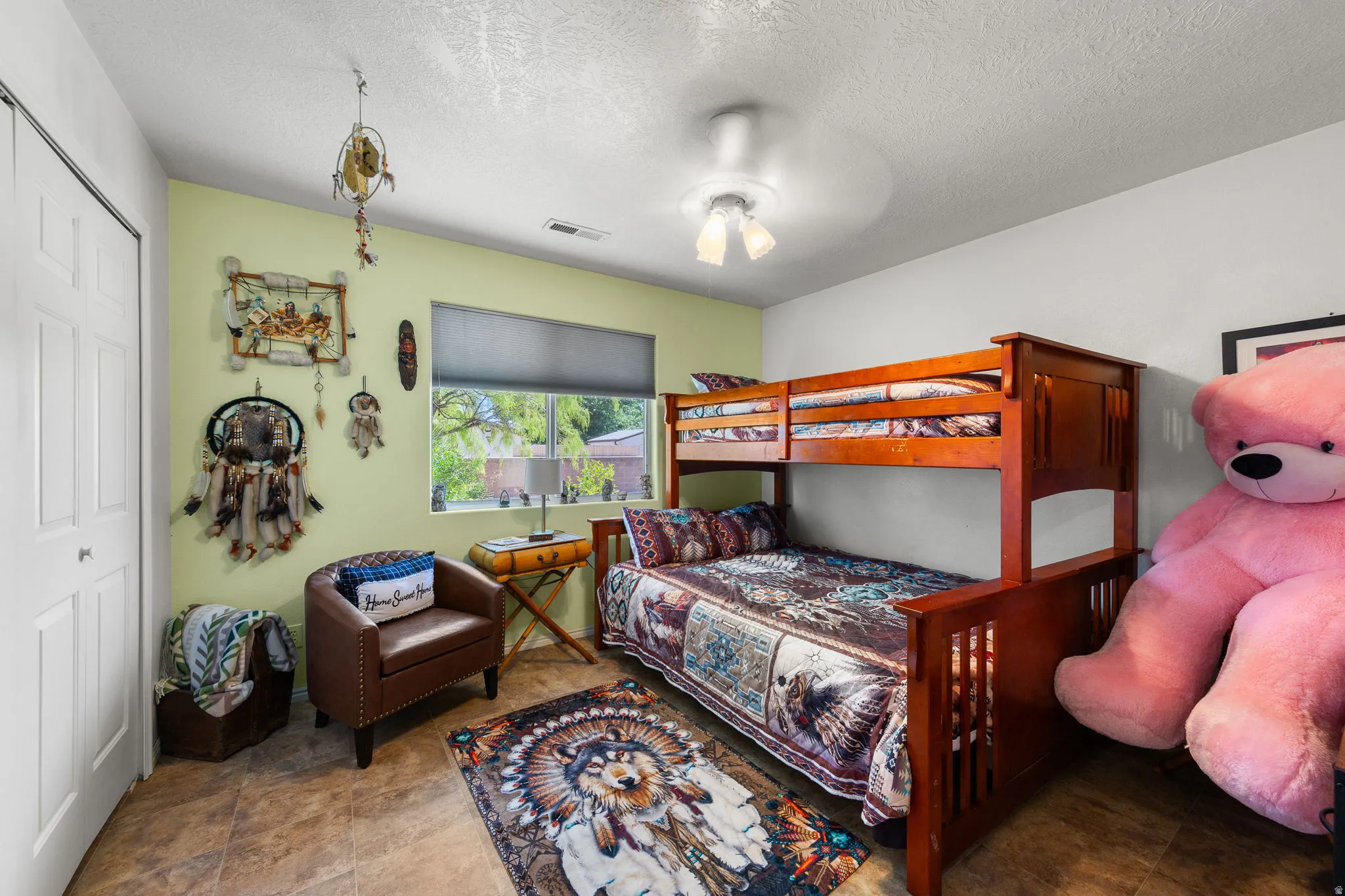 Room featuring tile-finish flooring, a double-door closet, a window with a roller blind, and a ceiling-mounted light fixture