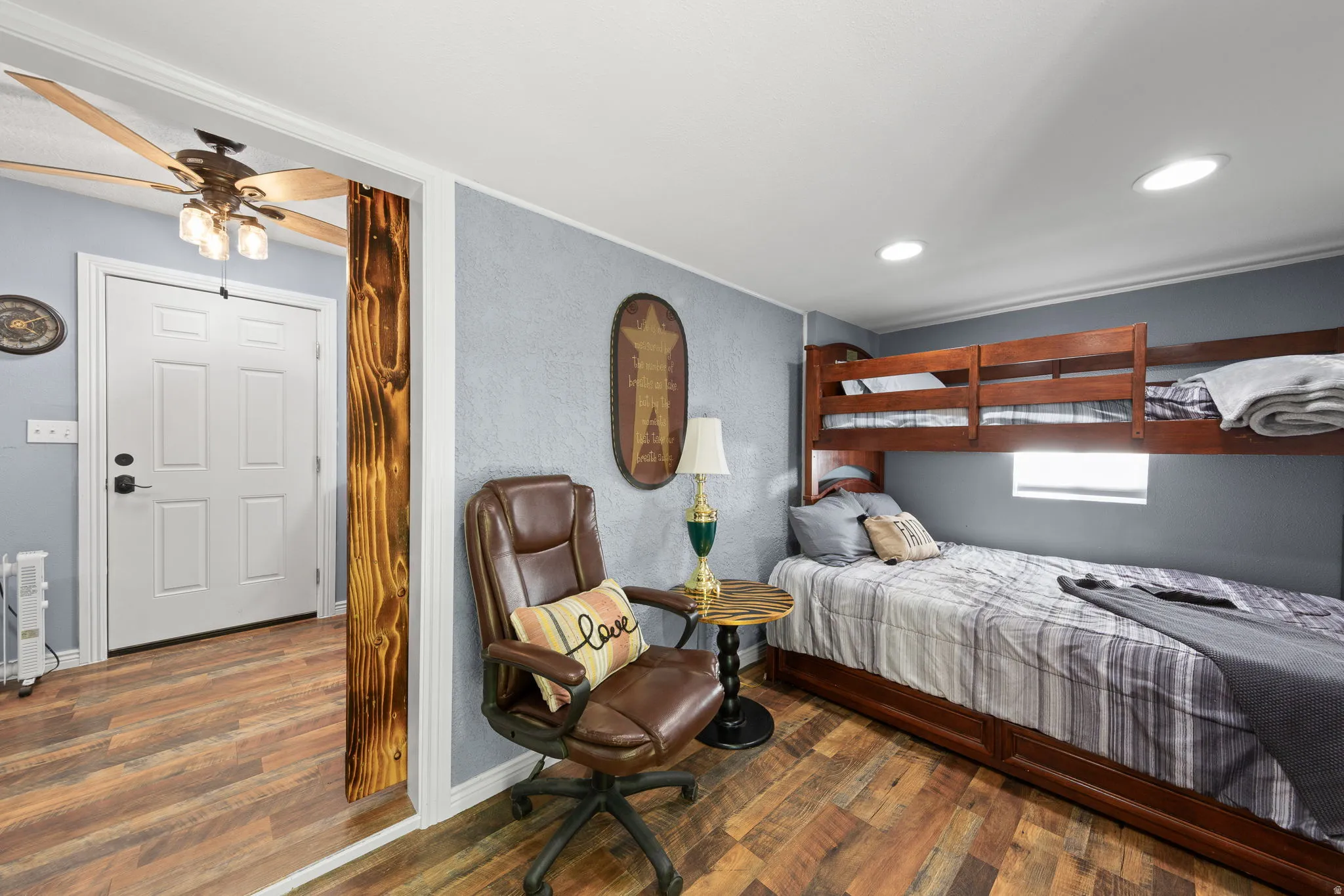 Recessed lighting illuminates this space featuring wood-finish flooring and textured blue walls