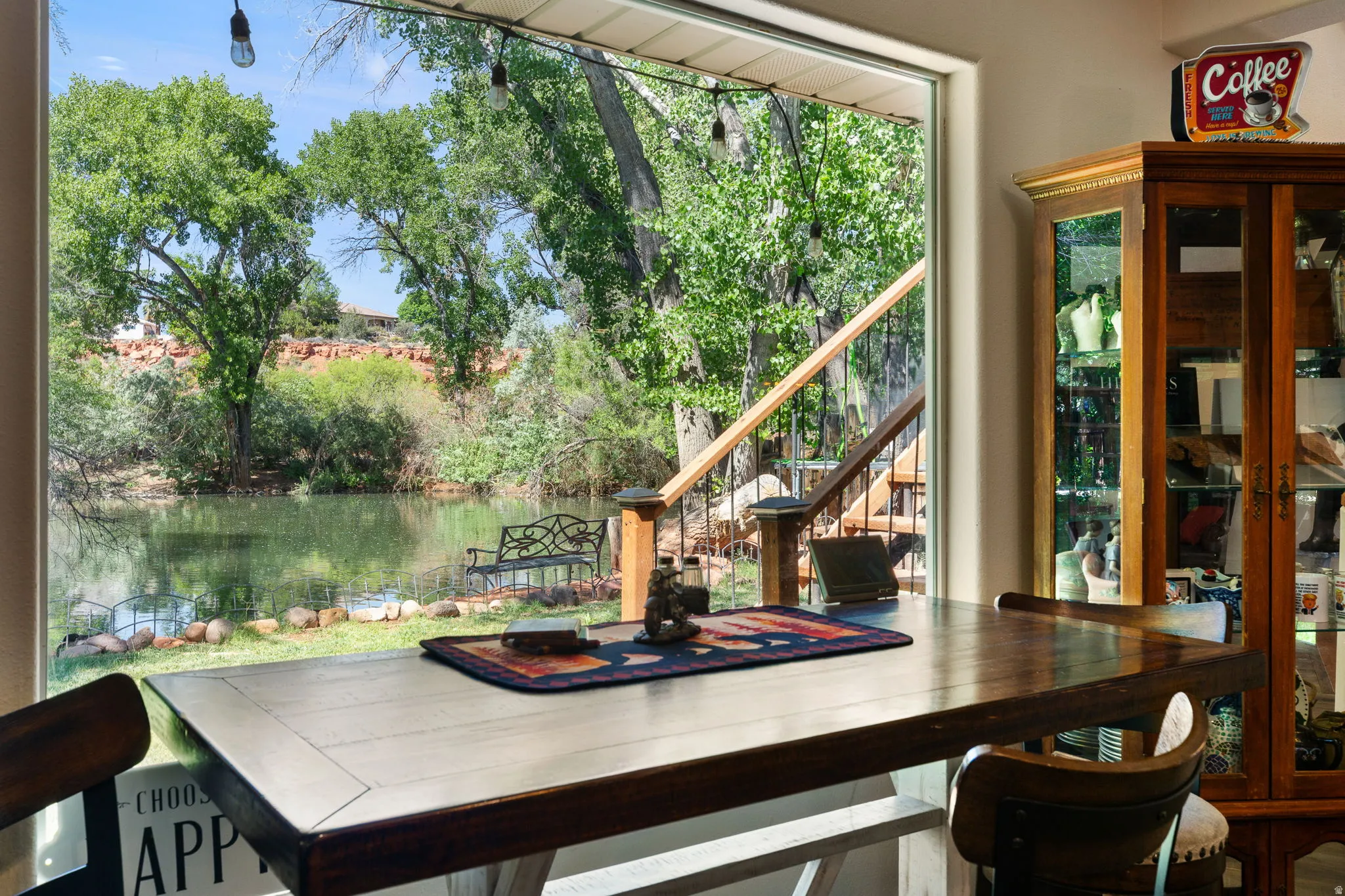 Expansive window overlooking a body of water with lush greenery and distant red rock formations