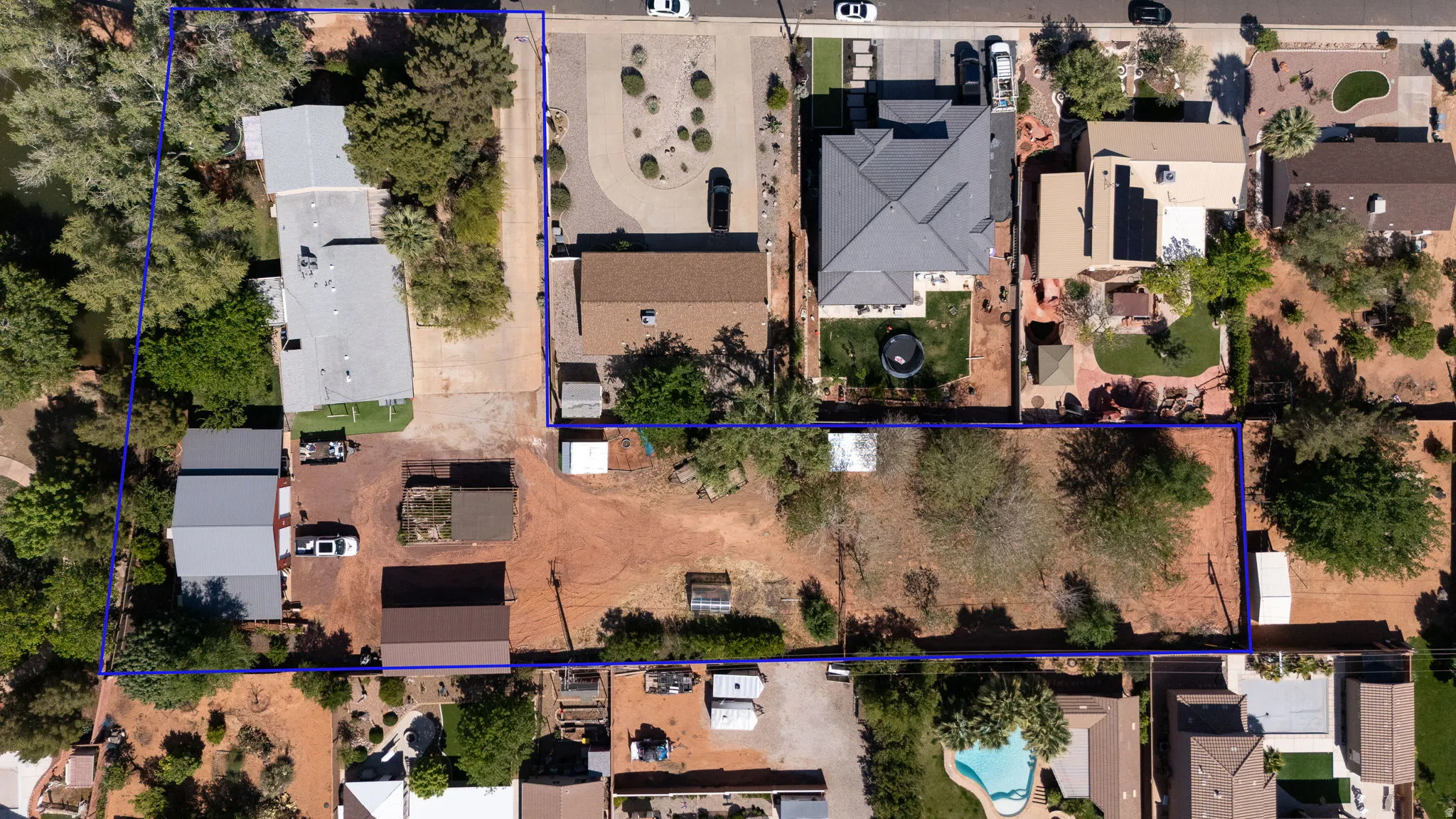 Expansive land parcel featuring existing structures, mature trees, and direct street access