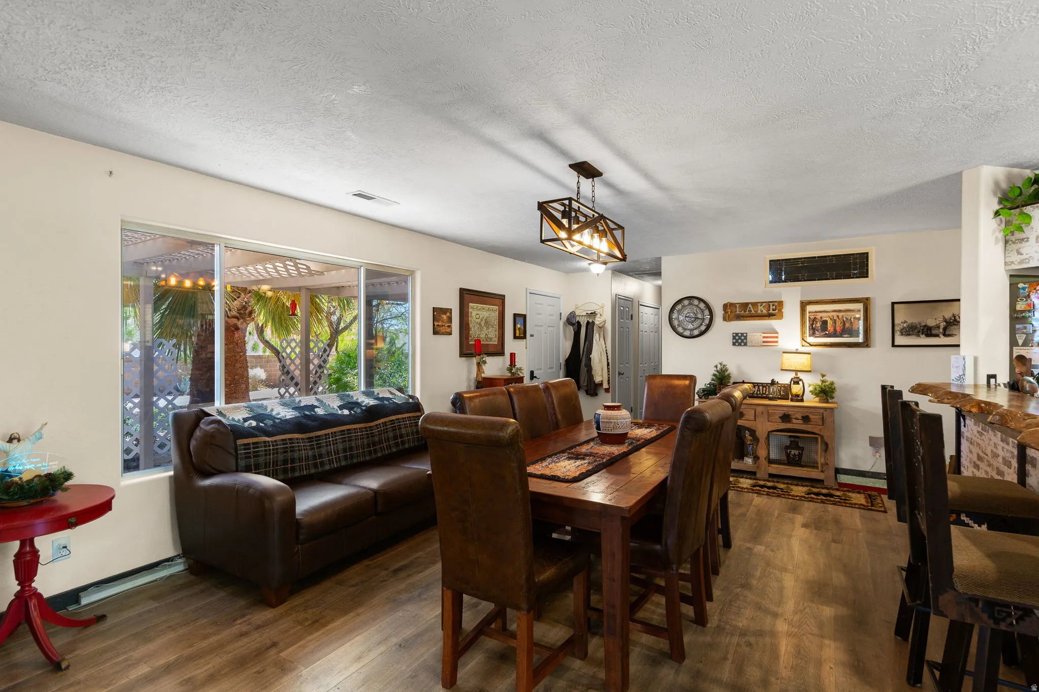 Open-concept common area featuring wood-finish flooring, a contemporary linear chandelier, and a breakfast bar with a live-edge countertop